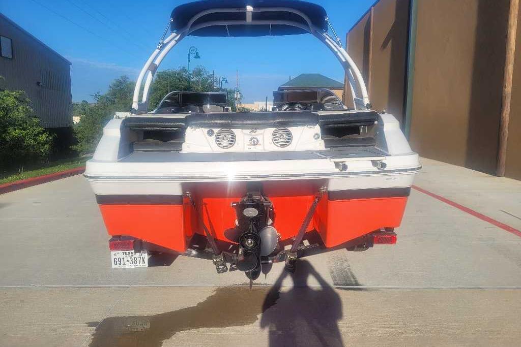 2016 Four Winns H200RS boat, rear view, parked on concrete, vibrant orange hull.