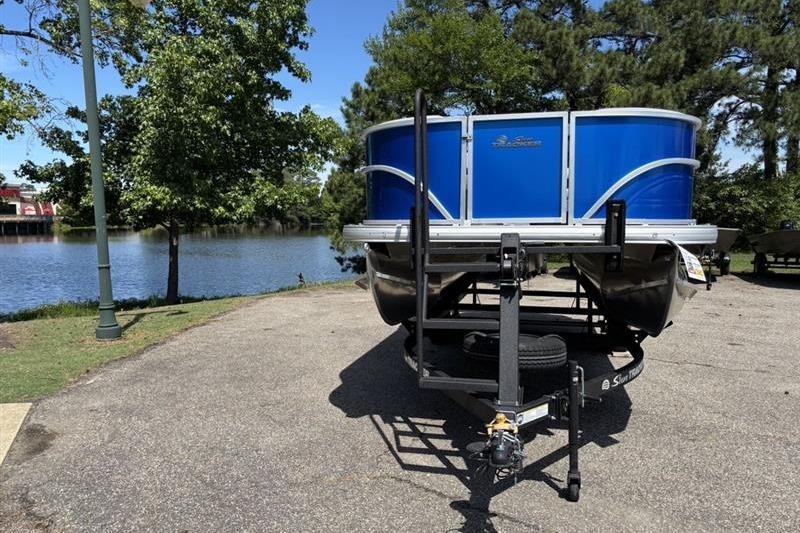 2026 Sun Tracker Party Barge 18 DLX pontoon boat parked by a scenic lake.