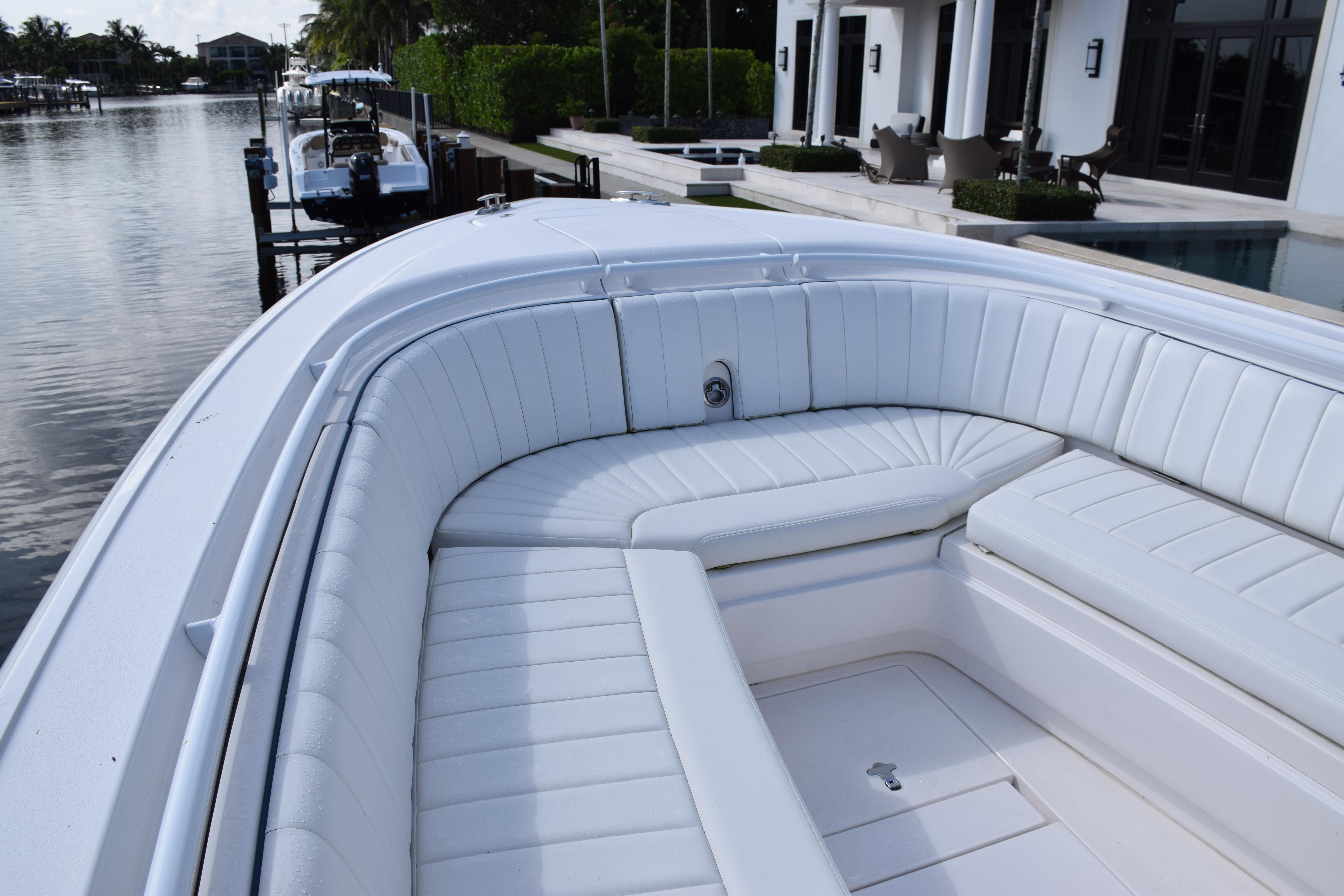 2017 Intrepid 327 boat with white cushioned seating, docked by waterfront homes.