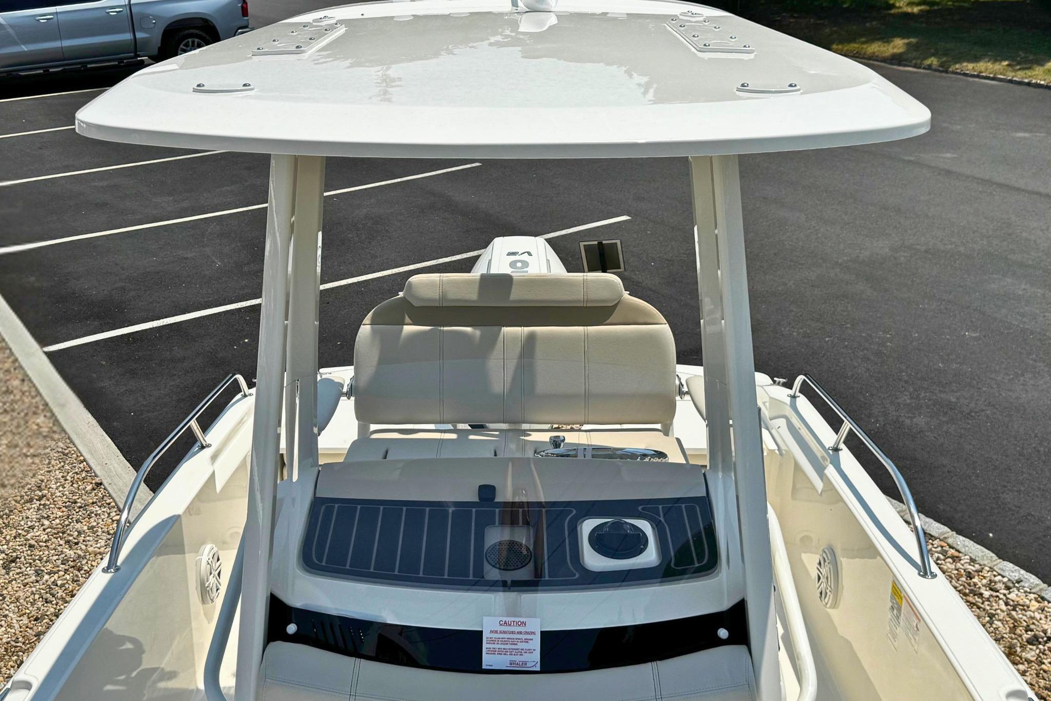 2026 Boston Whaler 220 Dauntless boat with T-top and seating, parked on asphalt.