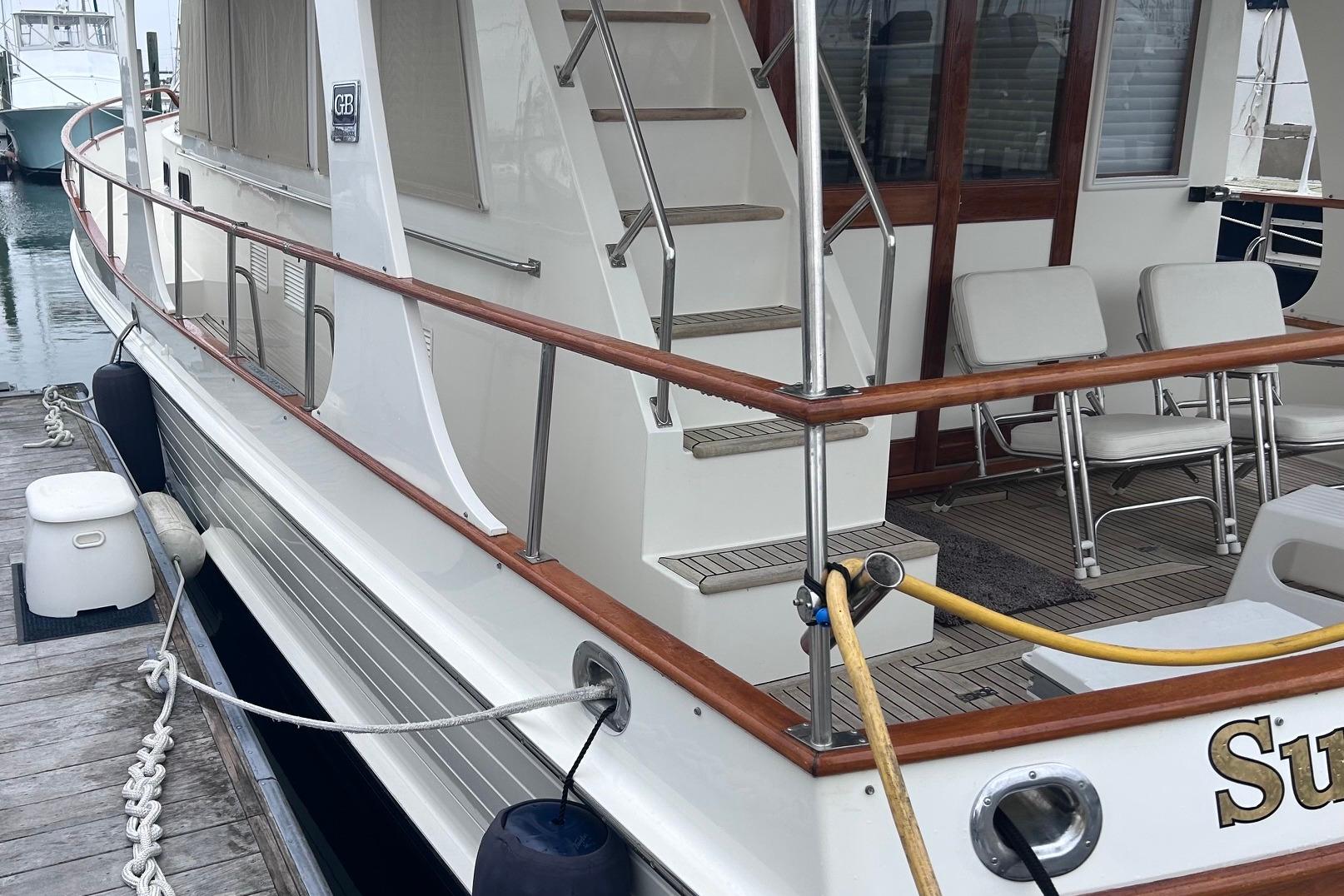 1999 Grand Banks 42 Europa yacht docked, featuring wooden railings and outdoor seating.