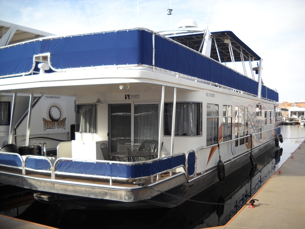 2006 Sharpe Makena Share 5 houseboat docked with blue canopy and outdoor seating.