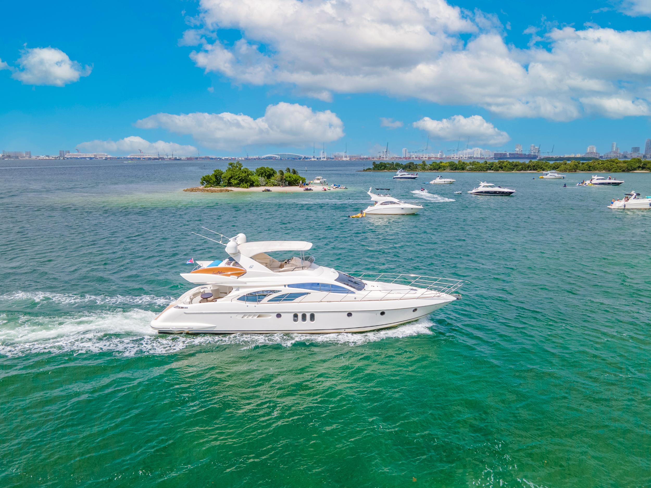 2004 Azimut 62 yacht cruising in clear blue waters under a sunny sky.
