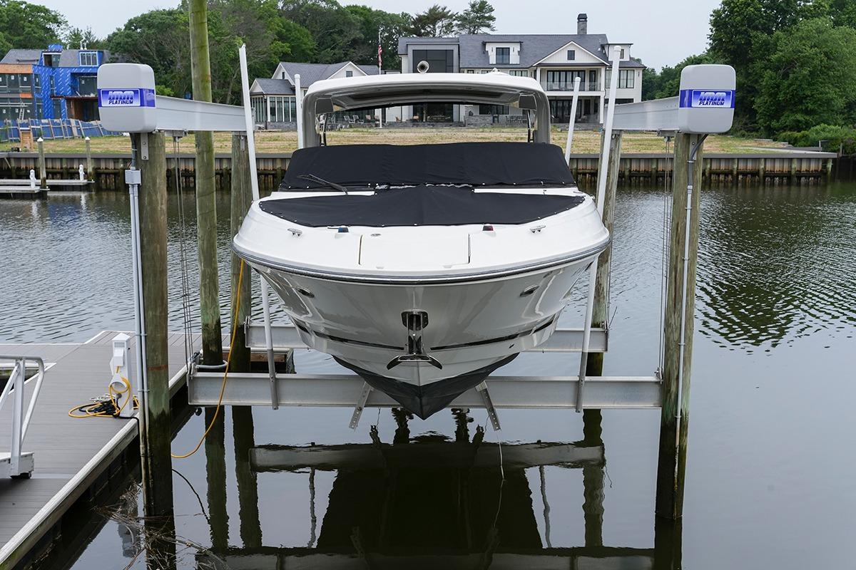 2018 Sea Ray SLX 350 boat on lift at dockside, waterfront homes in background.