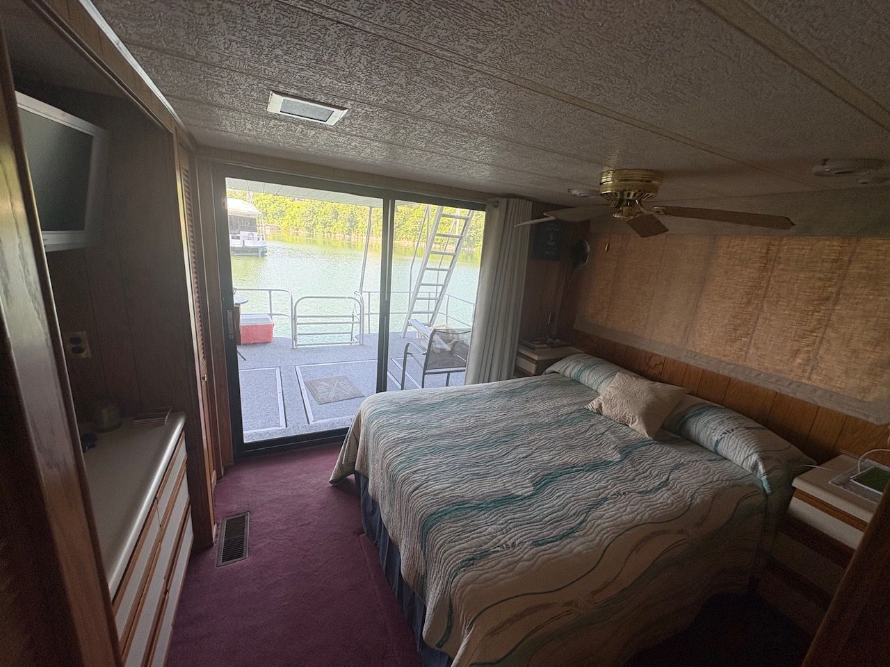A cozy bedroom on a houseboat with a large bed and a view of the water.