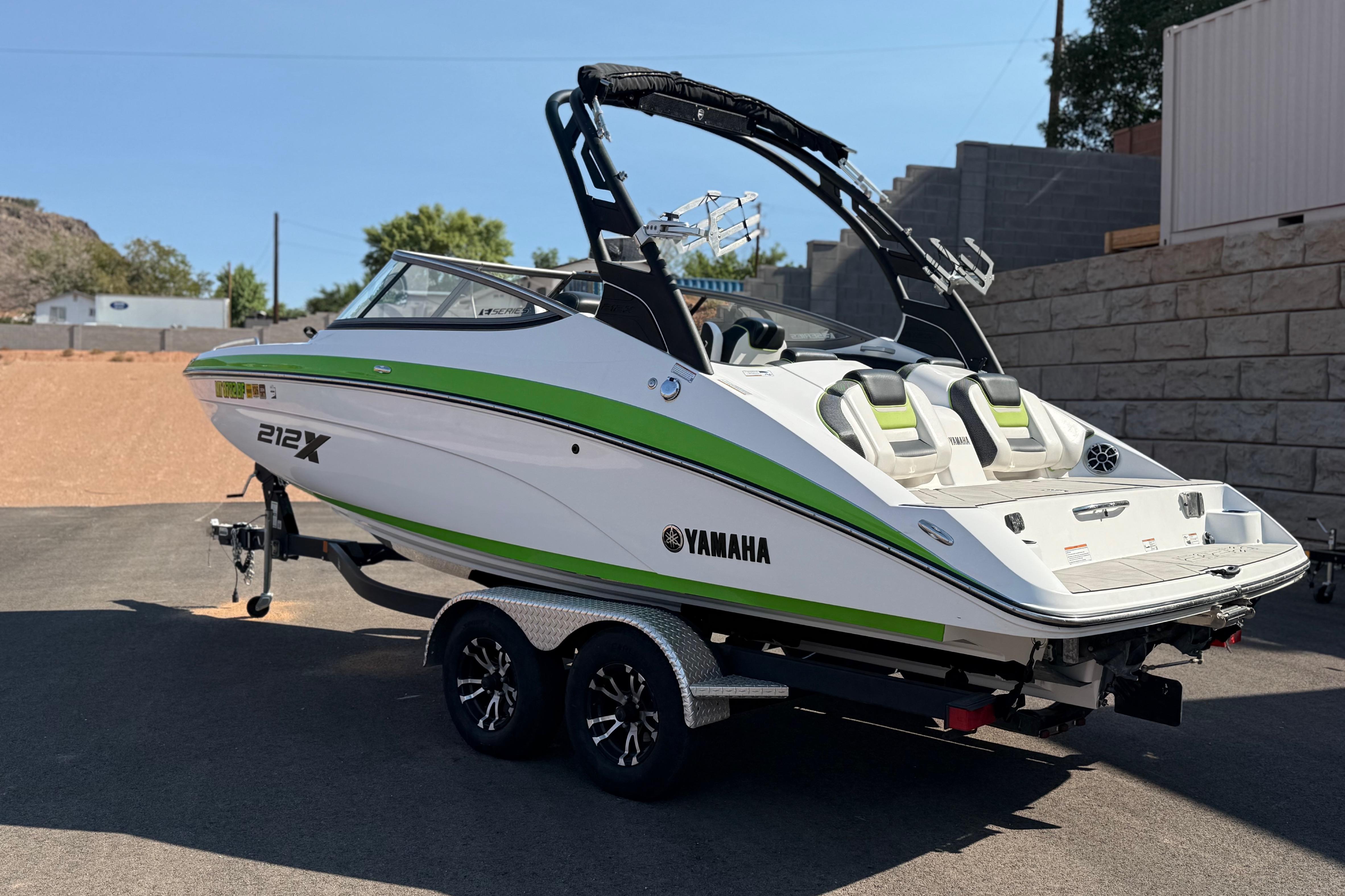2022 Yamaha Boats 212XE in white and green, parked on a trailer outdoors.