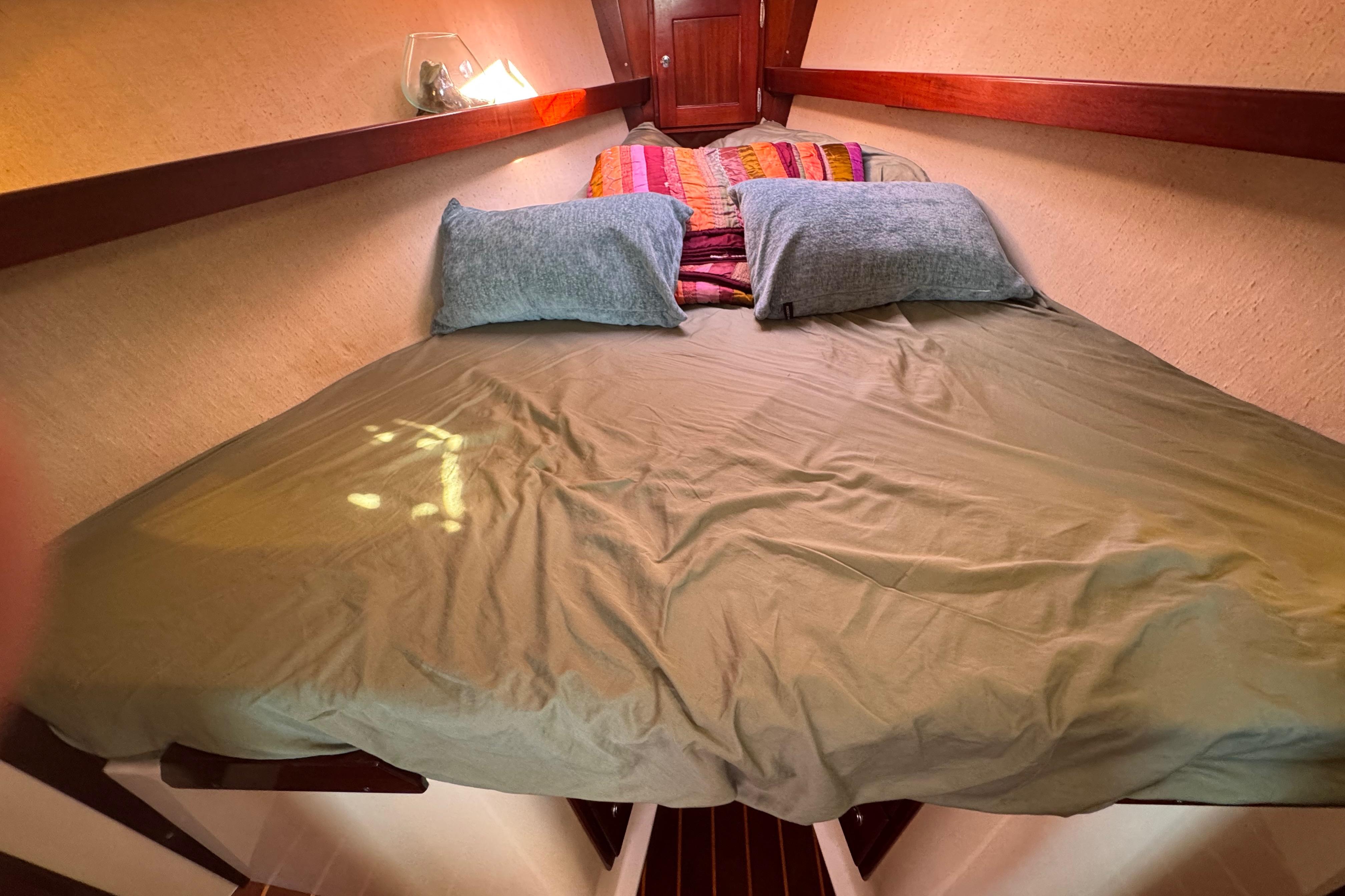 Cozy cabin interior of 2006 Shannon Shoalsailer with bed and colorful pillows.