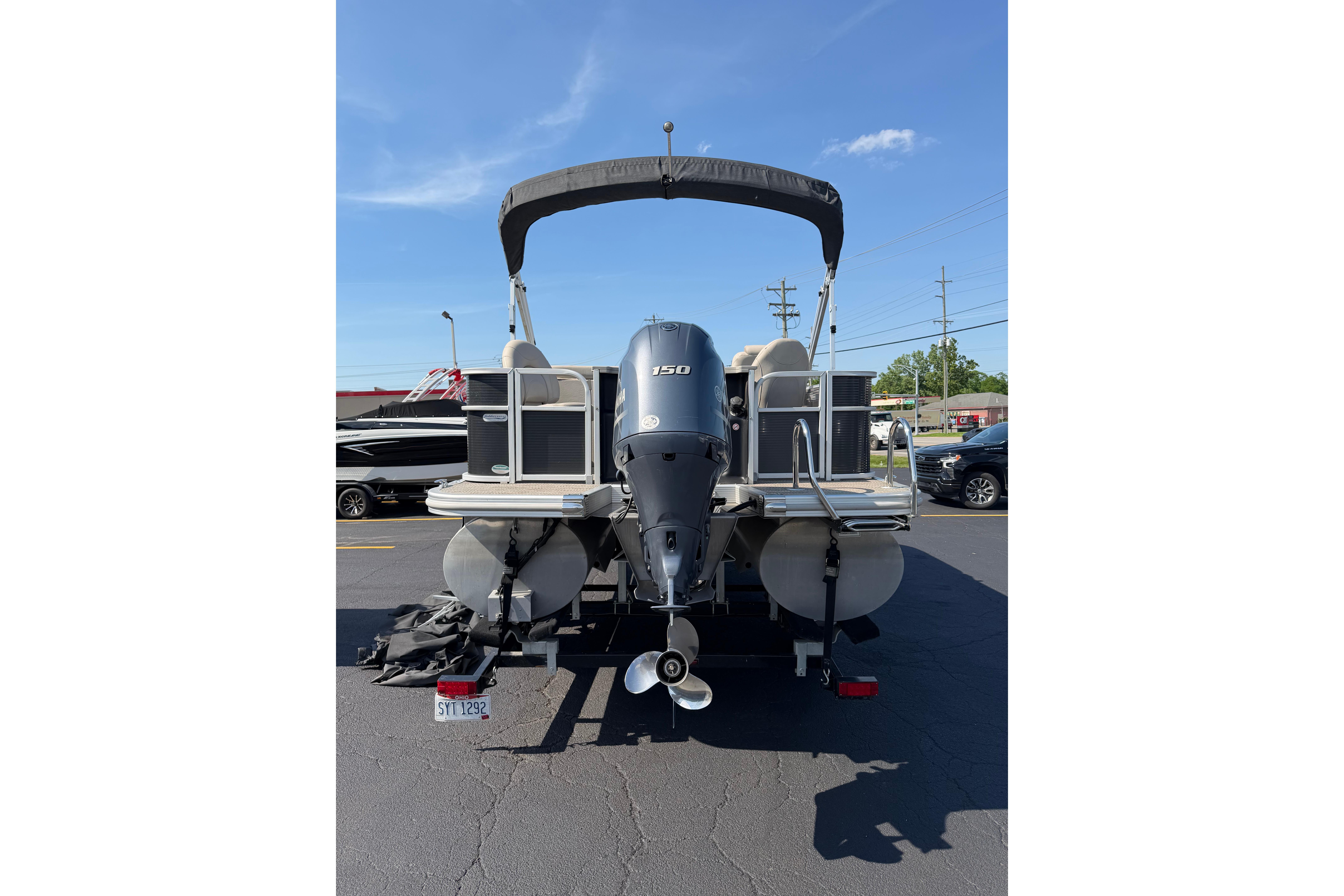 2018 Bennington 21 SF pontoon boat with outboard motor, parked on asphalt.