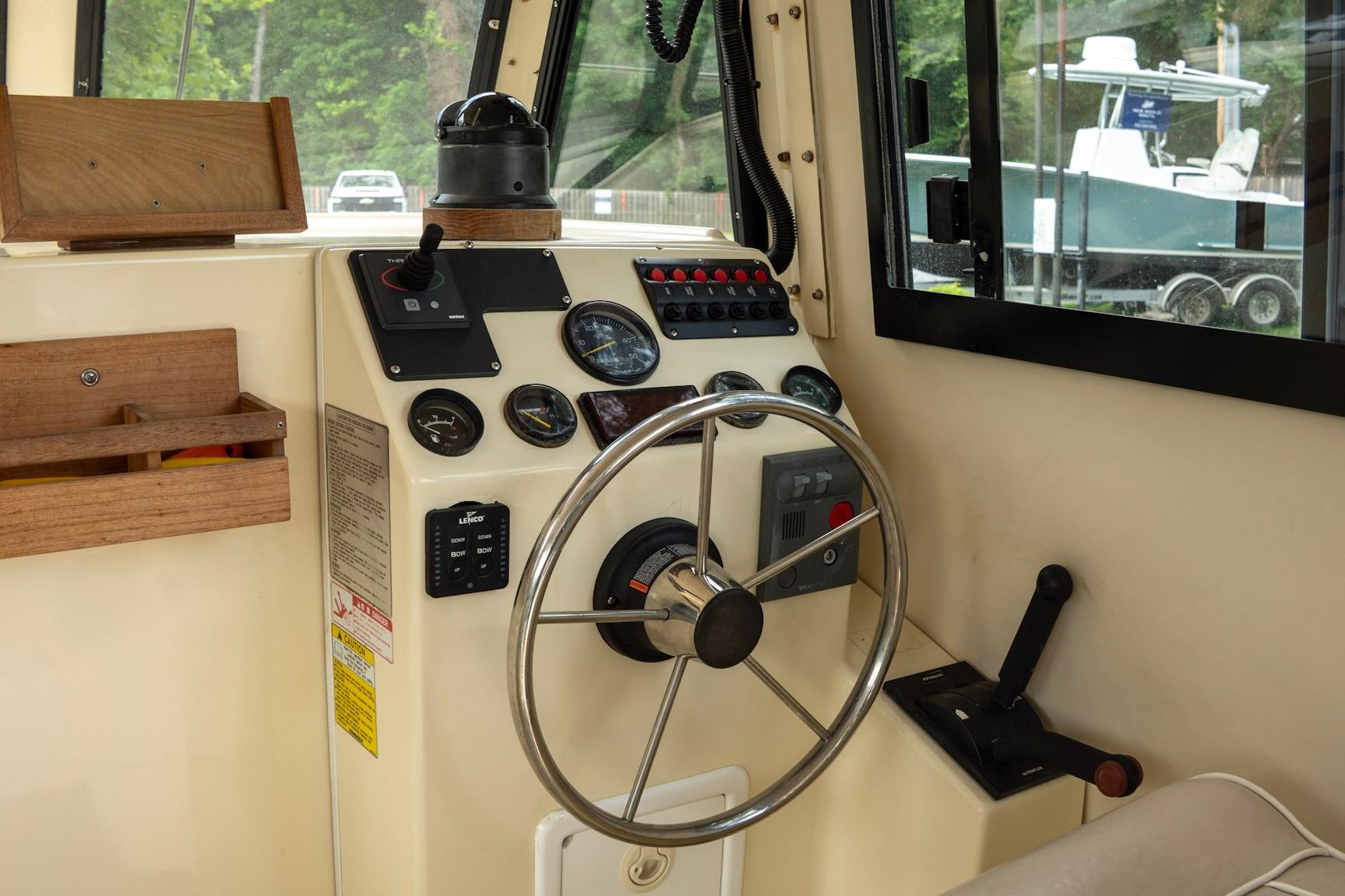 Interior helm of 2006 Atlas Boat Works Acadia 25, featuring steering wheel and control panel.