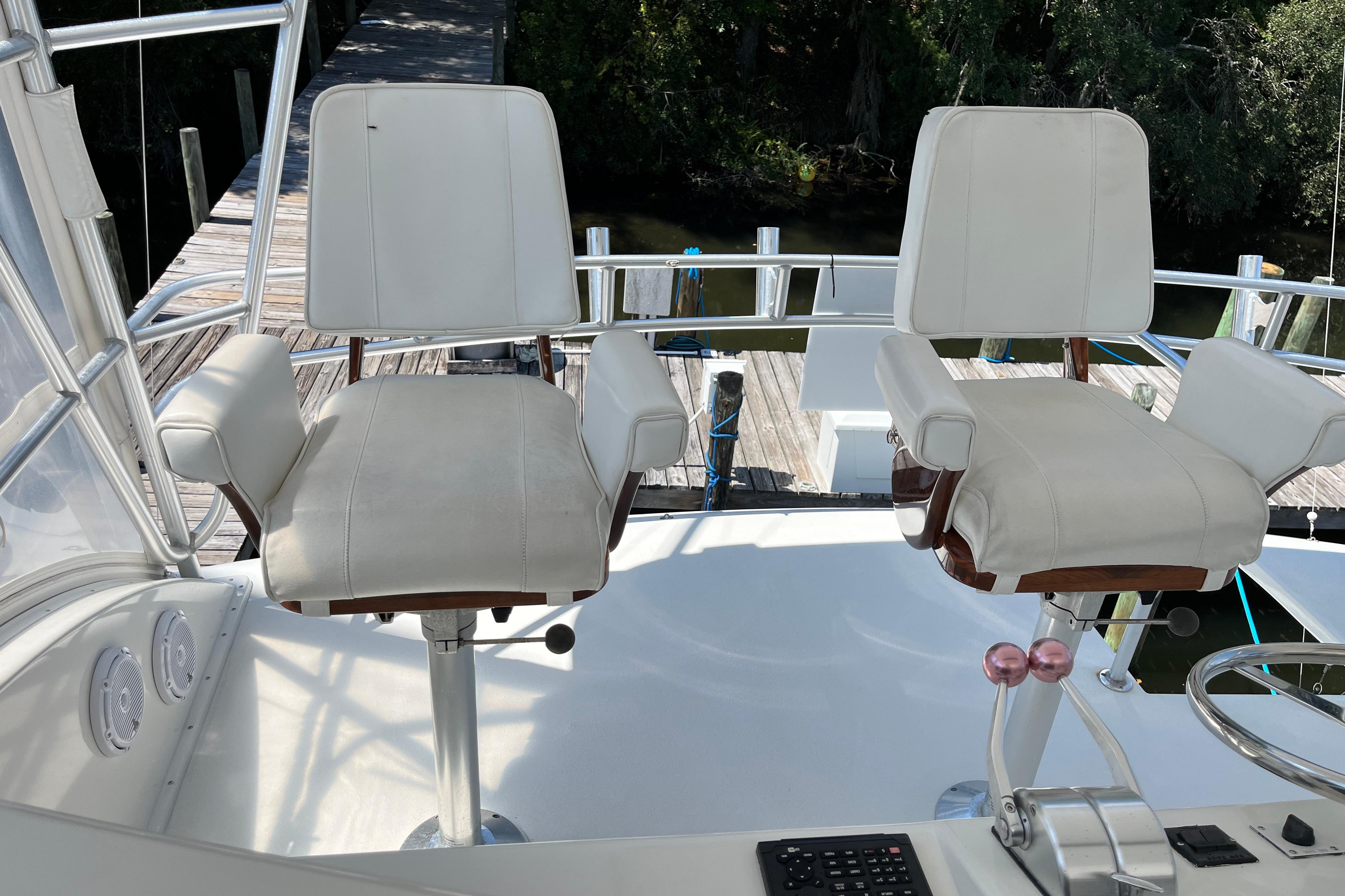 1997 Post Sportfish boat helm with two white captain chairs and control panel.