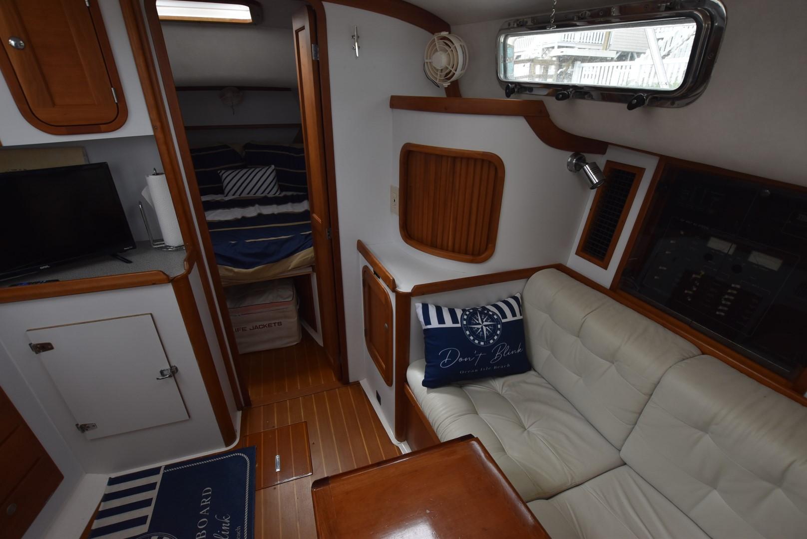 1999 Legacy 34 Express cabin interior with sofa, table, and cozy sleeping area.