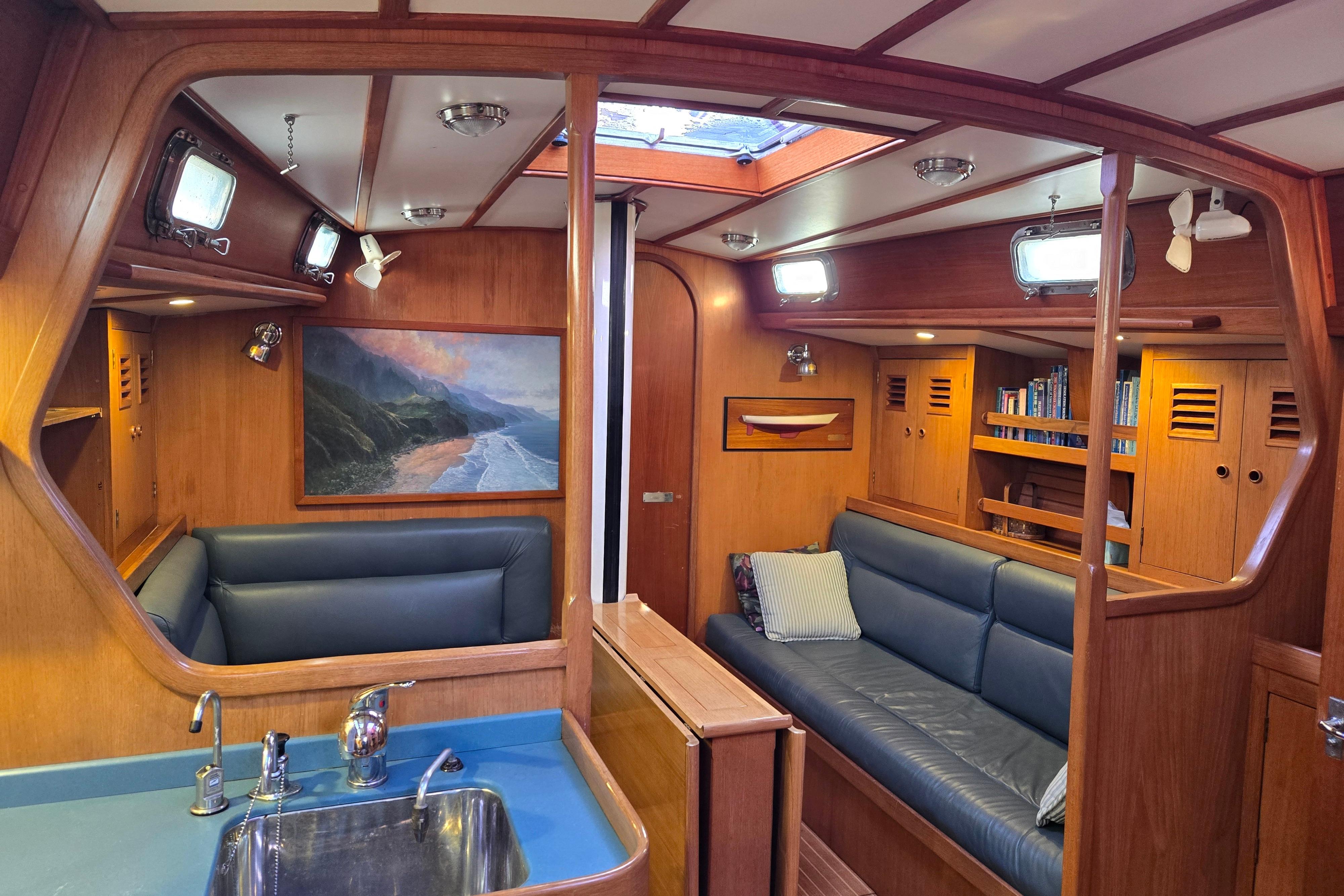Interior of 1986 Cambria 46 yacht with wood paneling and blue seating.