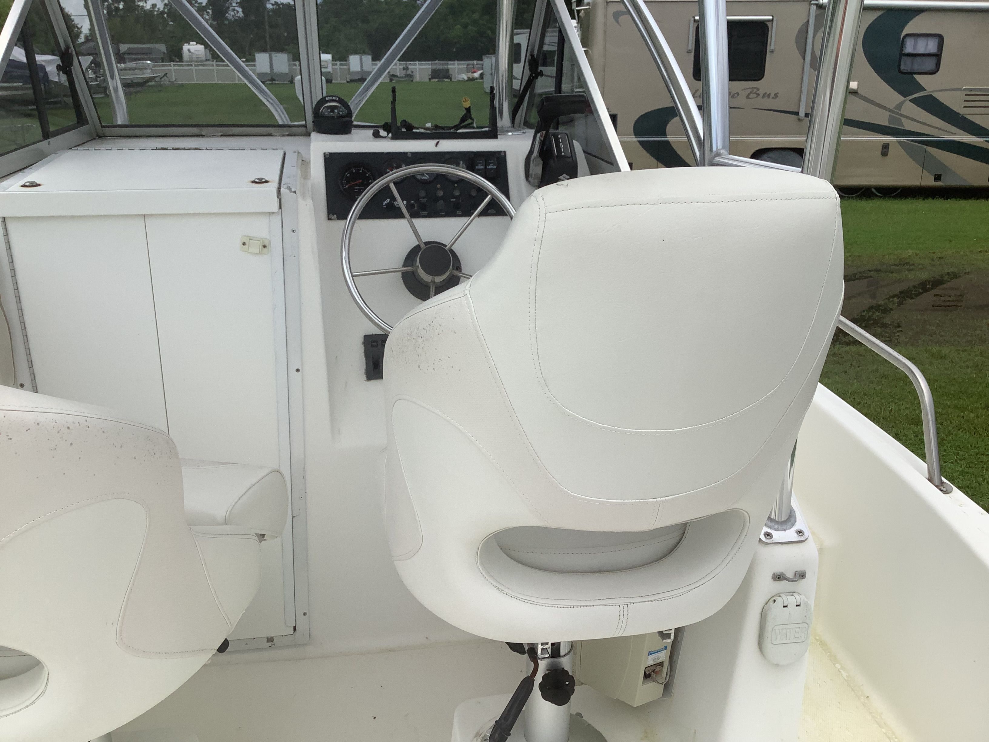 The image shows a boat's cockpit with white seats and a steering wheel.