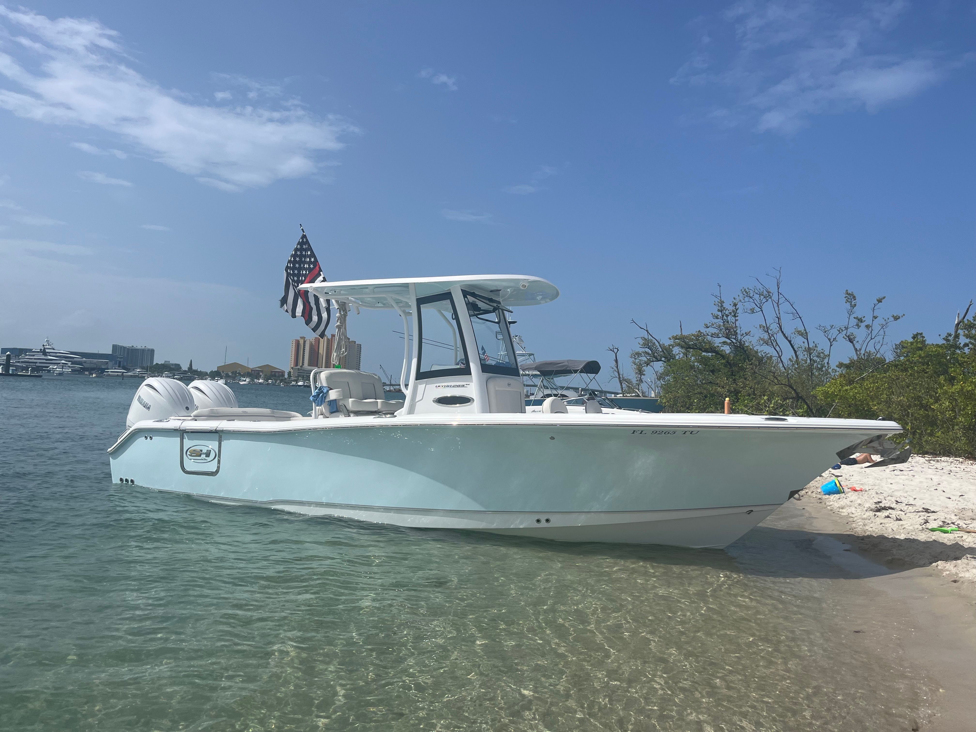 A 2024 Sea Hunt Ultra 265 SE boat is docked at the shore with an American flag.