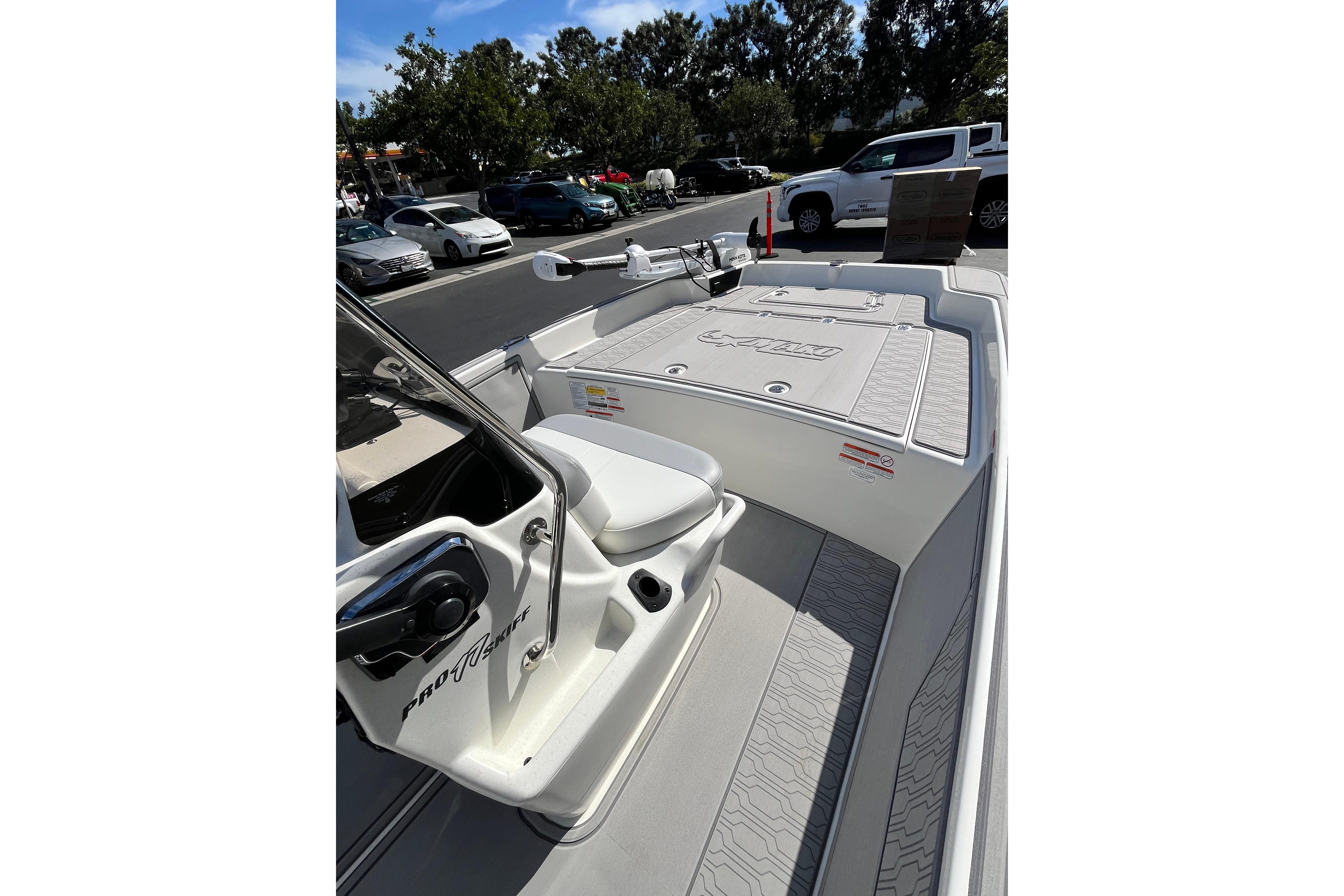 2026 Mako Pro Skiff 17 CC boat interior with seating and storage, parked outdoors.