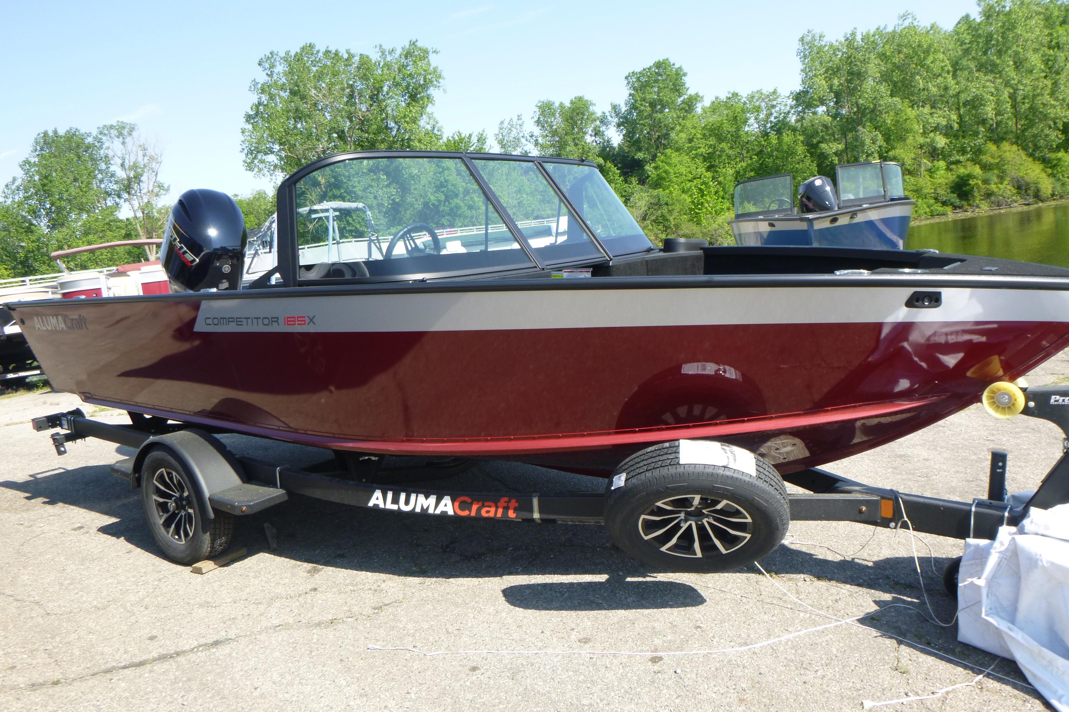 2024 Alumacraft Competitor 185X Sport boat on trailer, parked outdoors.
