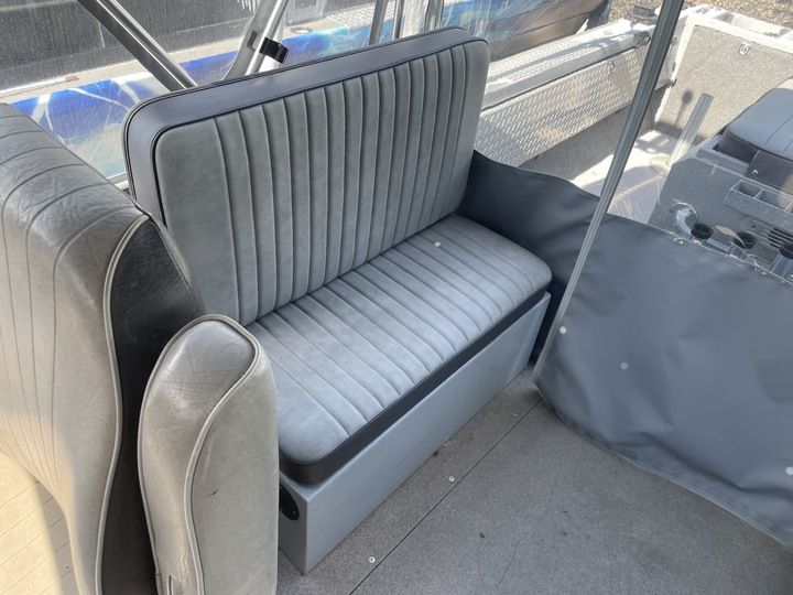 Gray, striped bench seat in a boat with gray flooring.