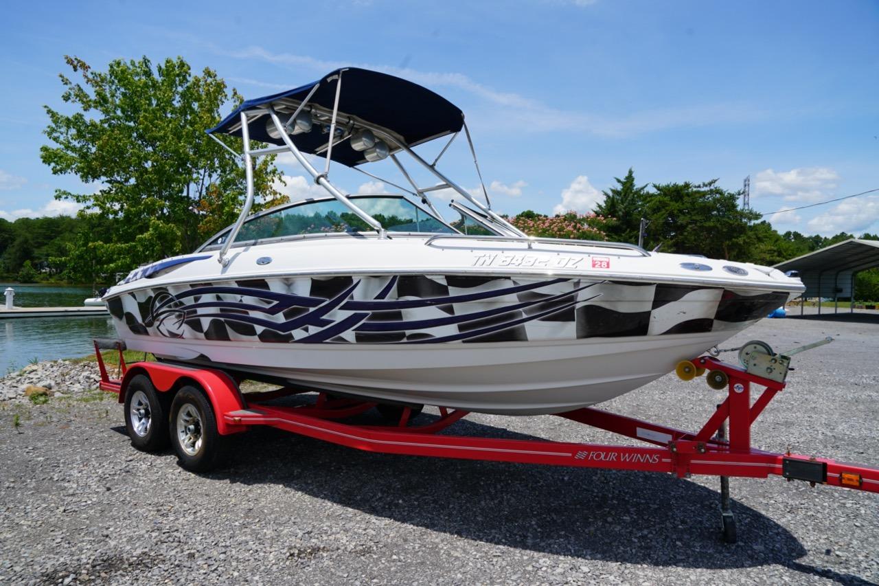 2004 Crownline 216 LS boat on red trailer, parked near a lake under a clear sky.