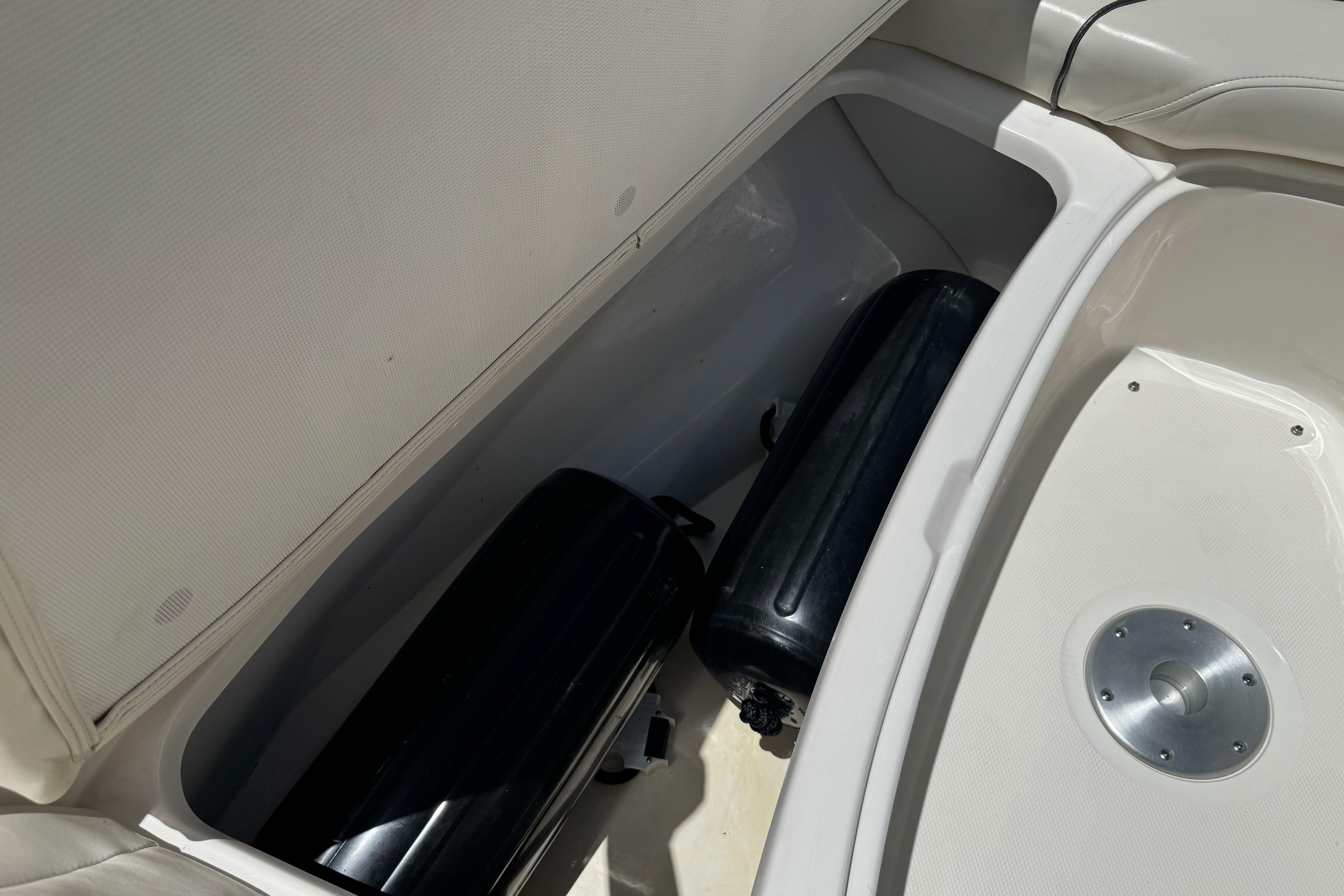 Storage compartment of a 2007 Sea Ray SLX 250 boat with black fenders inside.