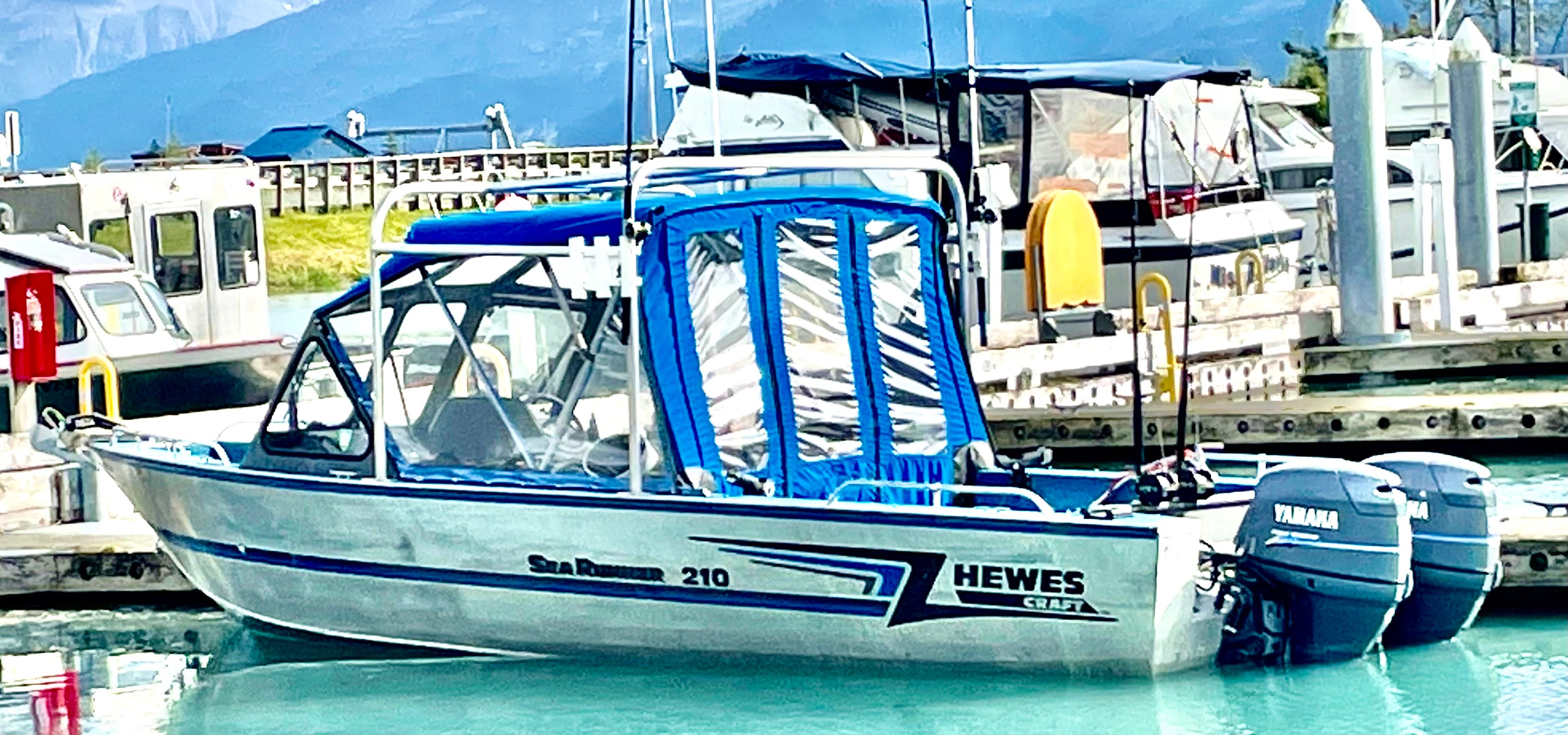 A Hewescraft Sea Runner 210 boat docked in a marina, surrounded by other boats.