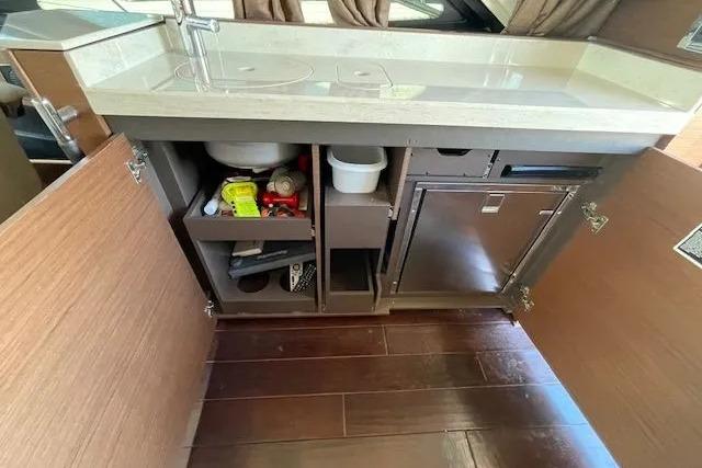 Interior view of 2016 Sea Ray Sundancer 510 kitchen cabinet with open doors.