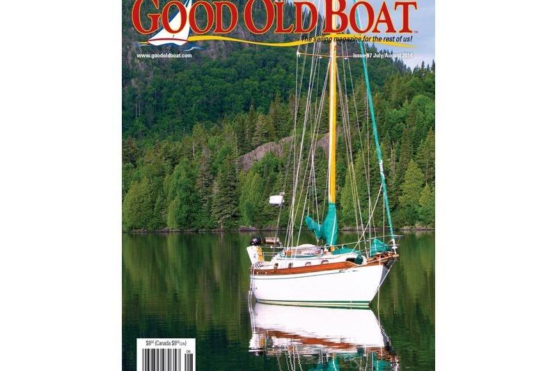 Sailboat on calm lake, surrounded by lush forest, featured on "Good Old Boat" magazine cover.