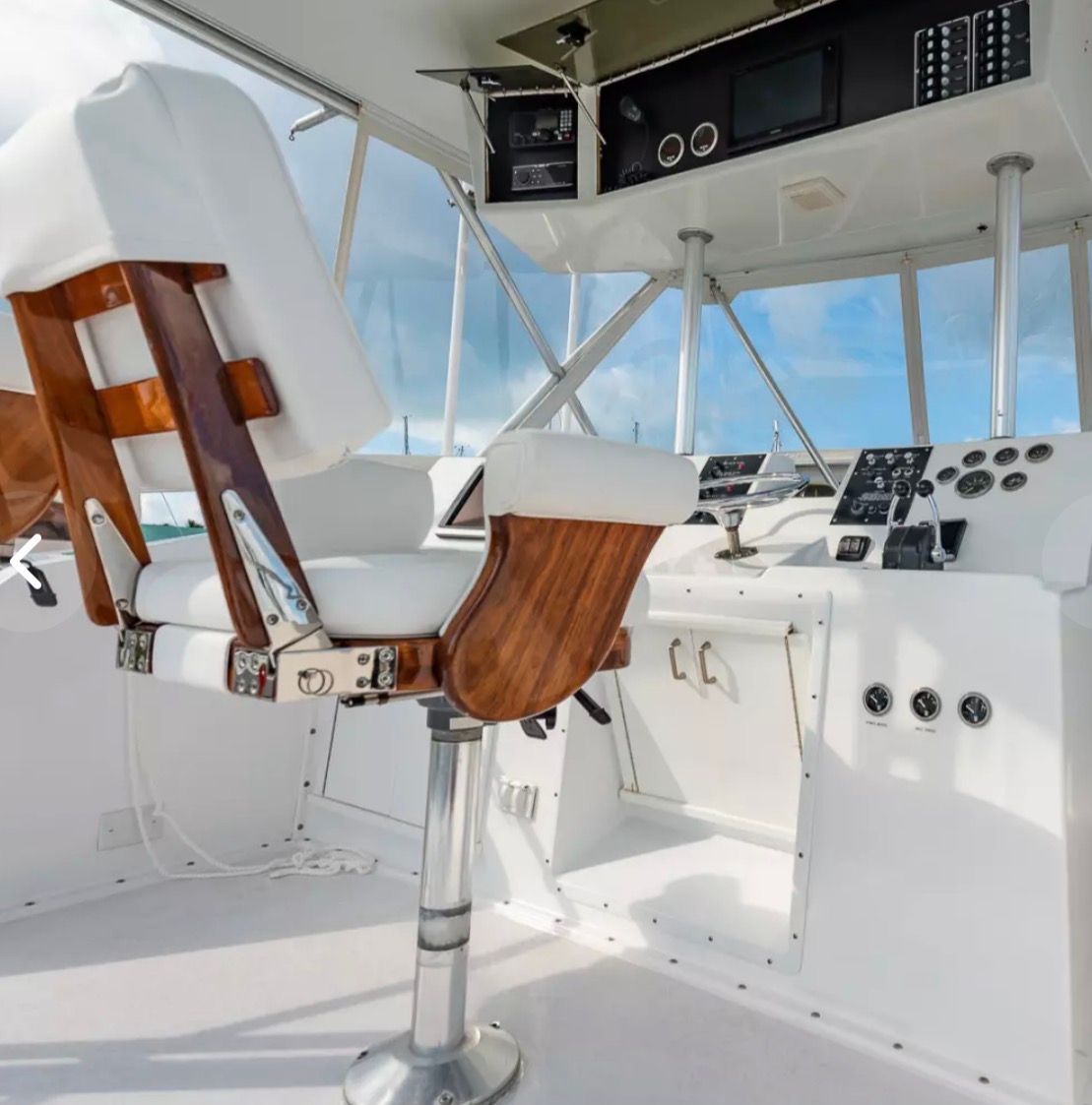 Interior of a 1979 Hatteras sport fishing boat with white helm and wooden accents.