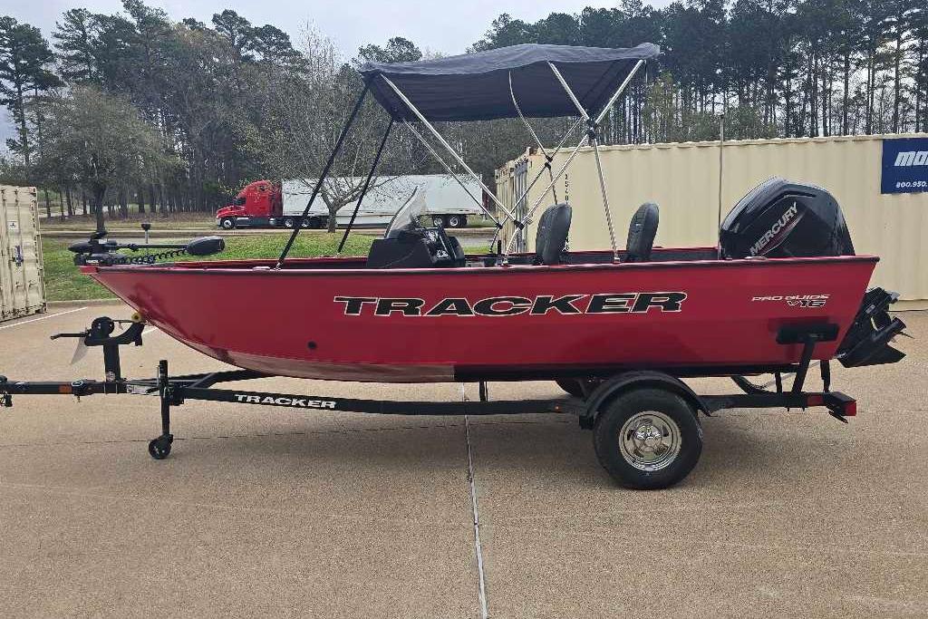 2026 Tracker Pro Guide V-16 SC boat on trailer, red with canopy, parked outdoors.