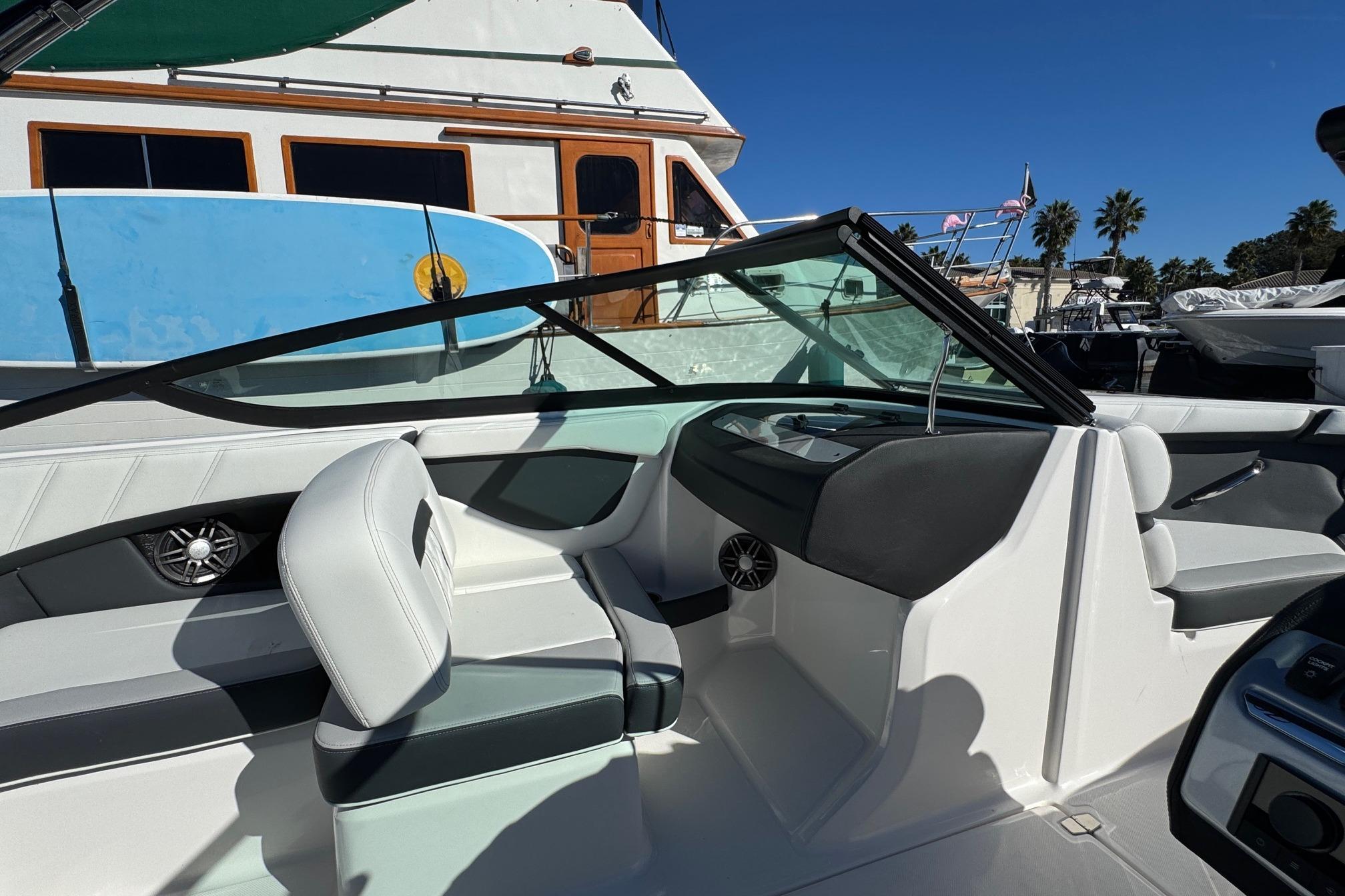2026 Regal 21 OBX boat interior with seating and dashboard, docked near other boats.