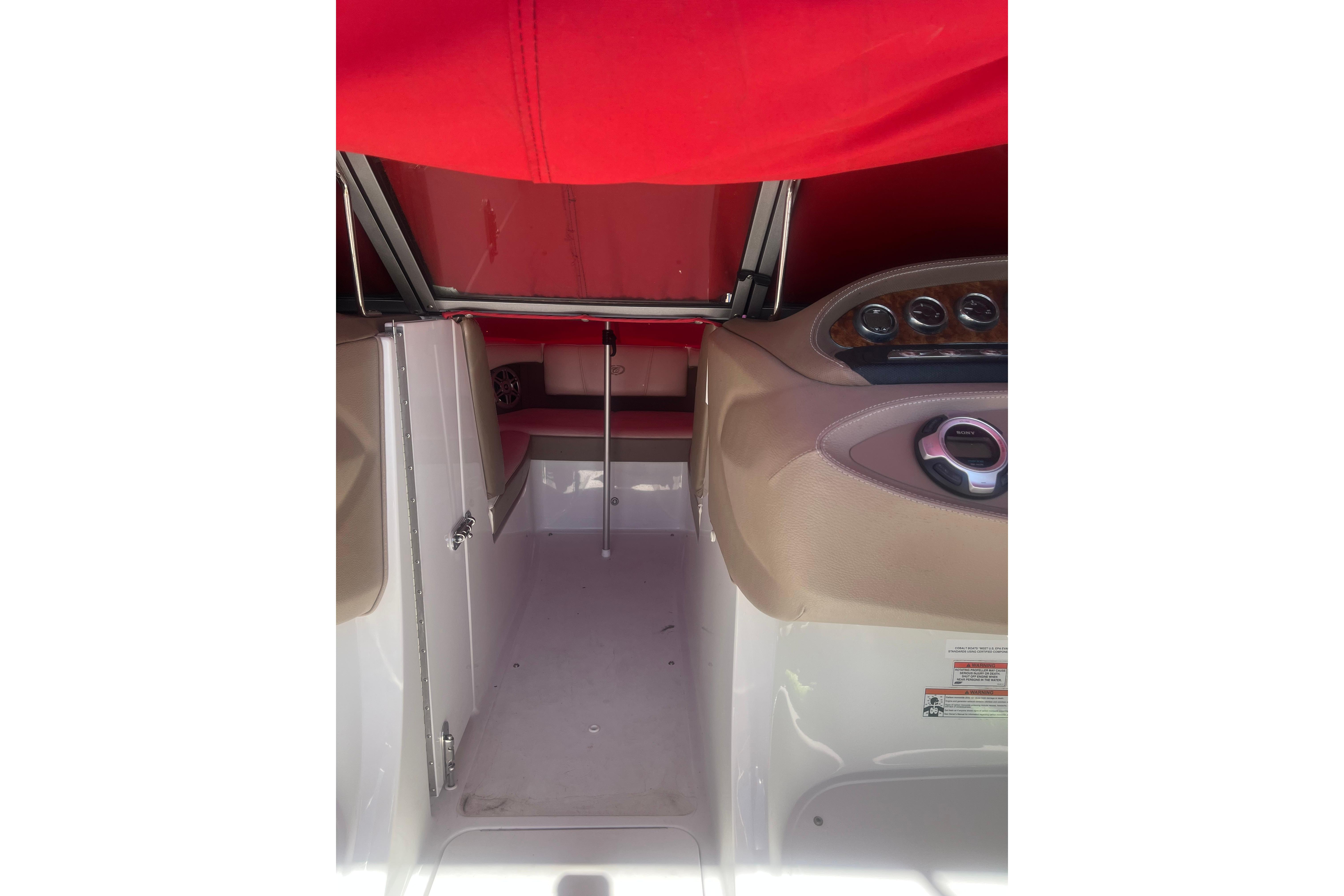 Interior view of a 2011 Cobalt 210 boat with red canopy and beige dashboard.