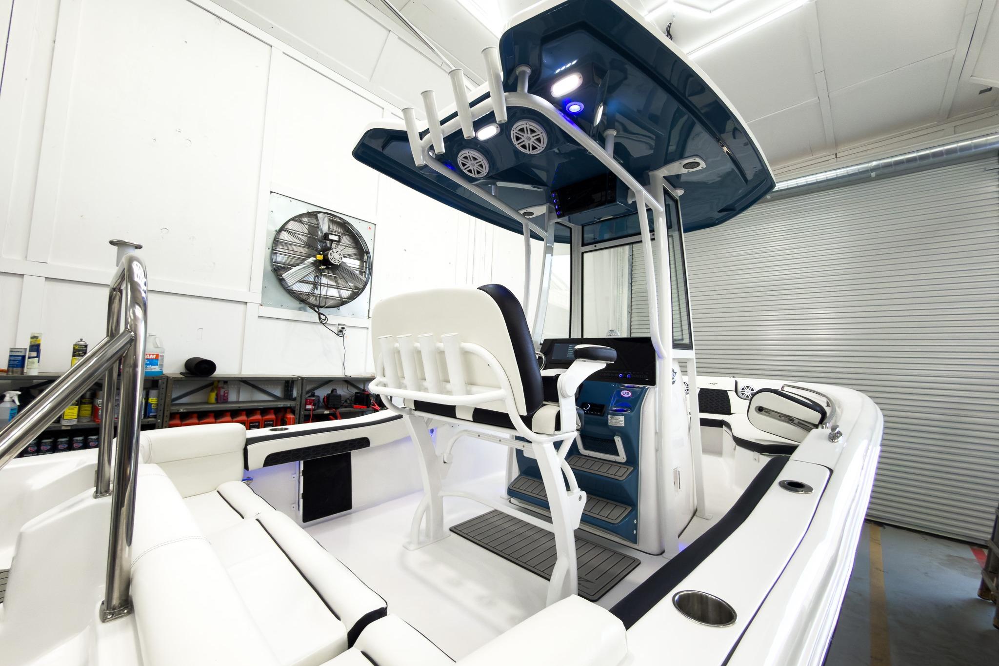 The image shows a modern boat with a blue canopy and white seating in a garage.