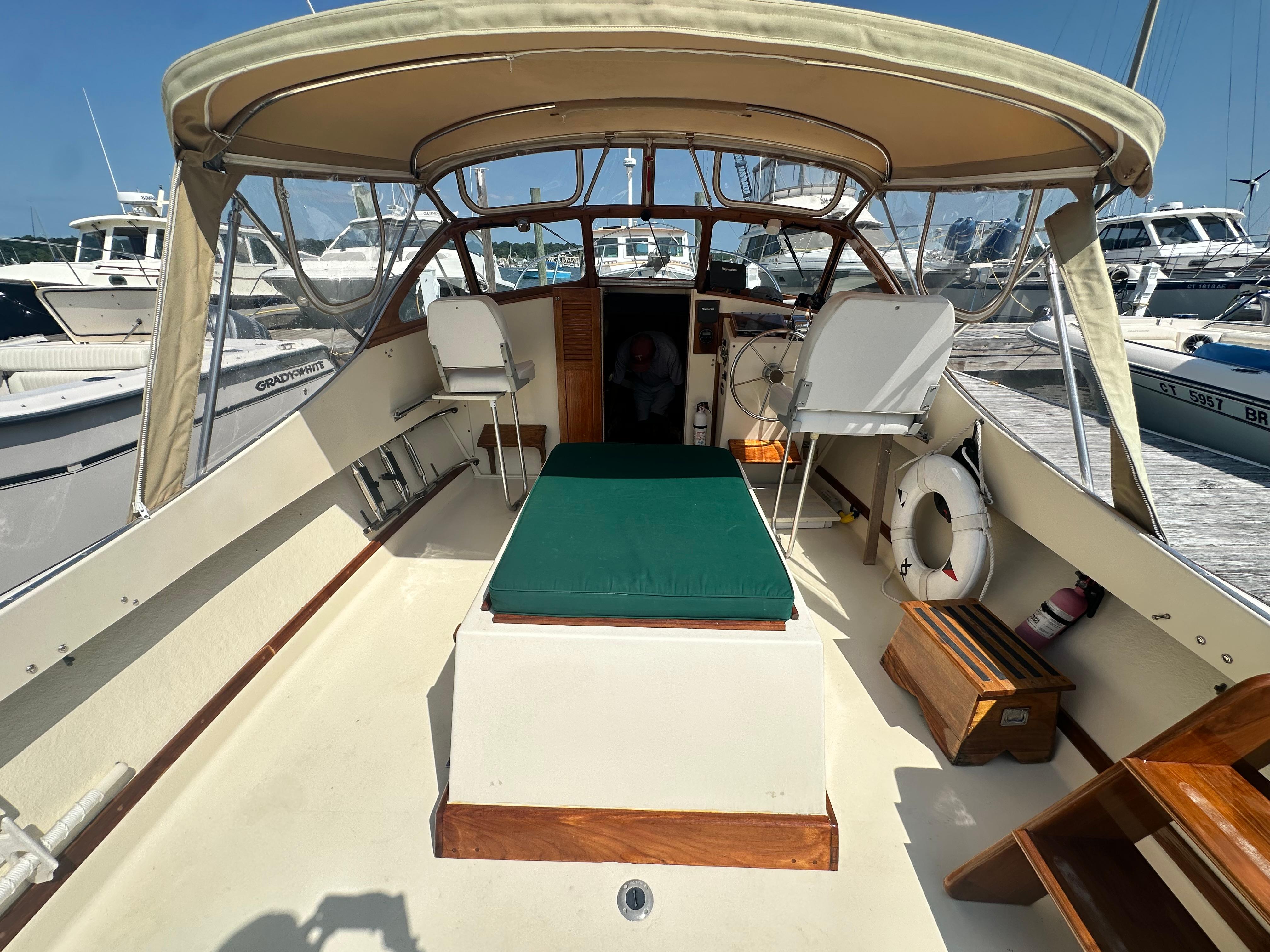 1979 Fortier 26 boat interior with canopy, seating, and steering wheel at marina.