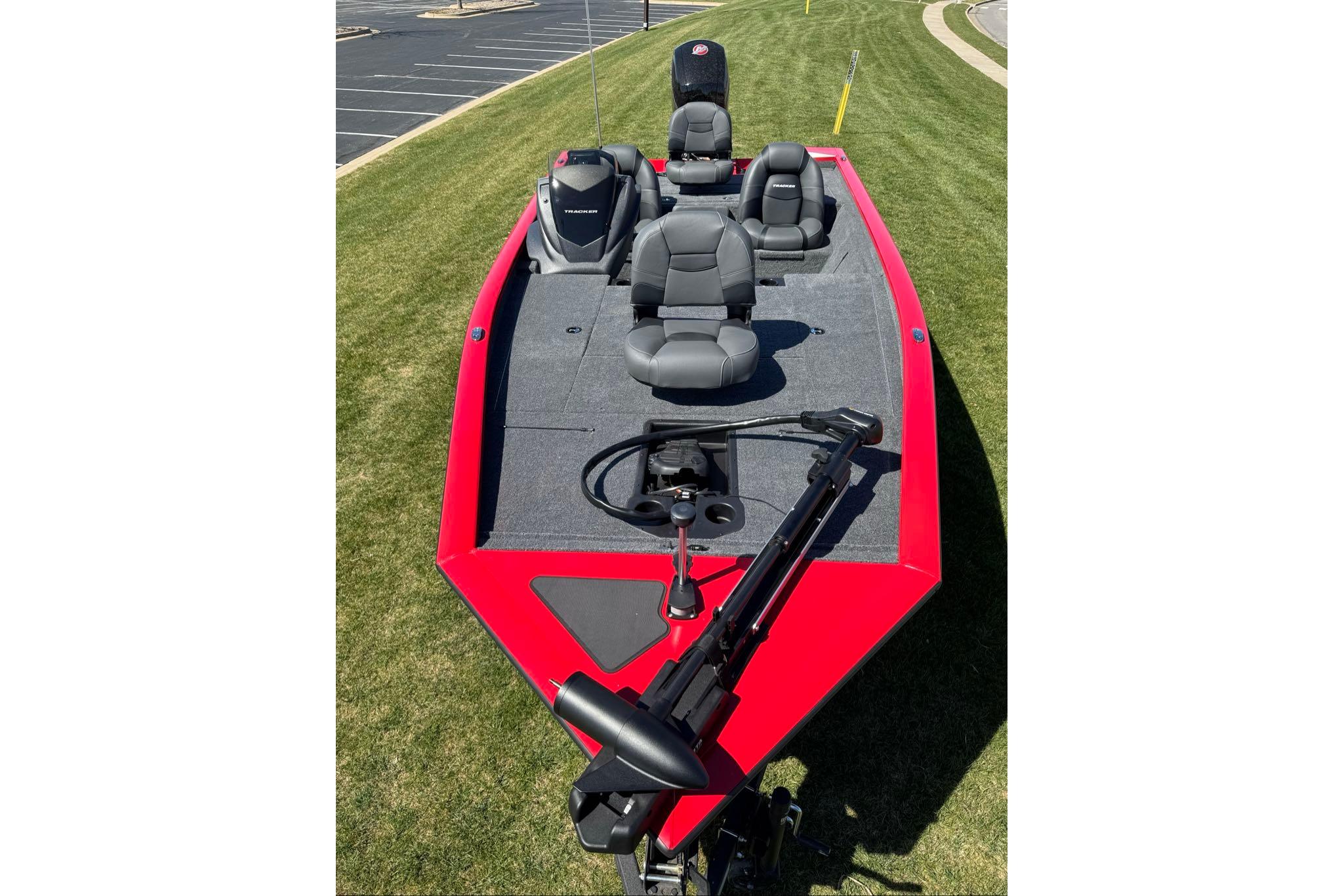 2026 Tracker Pro Team 195 boat with red exterior and gray seating on grass.