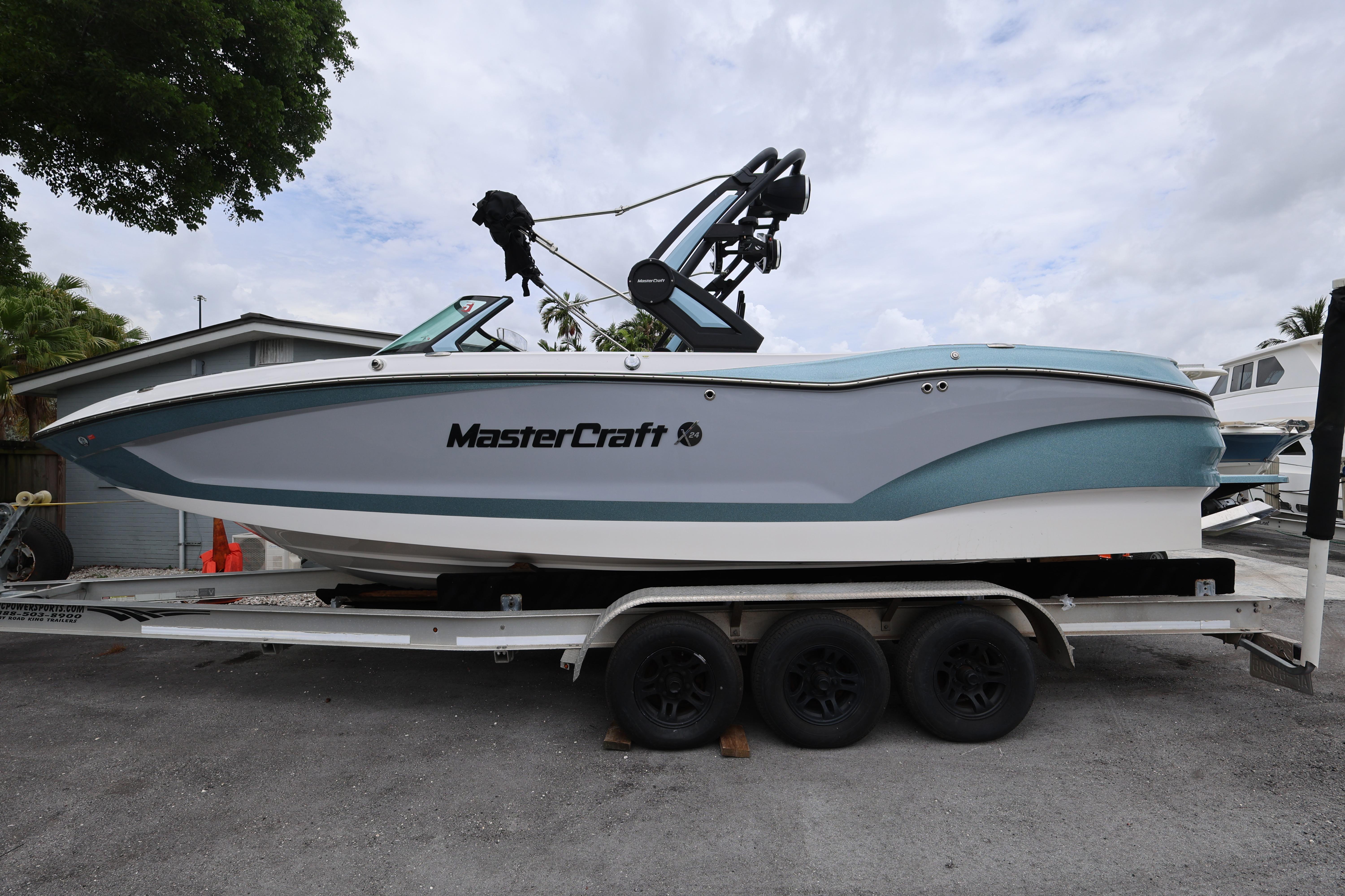 2023 MasterCraft X24 boat on trailer, side view, parked outdoors.