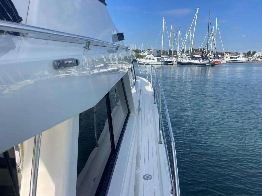 1985 Princess Sedan Flybridge yacht docked in a marina with sailboats in the background.