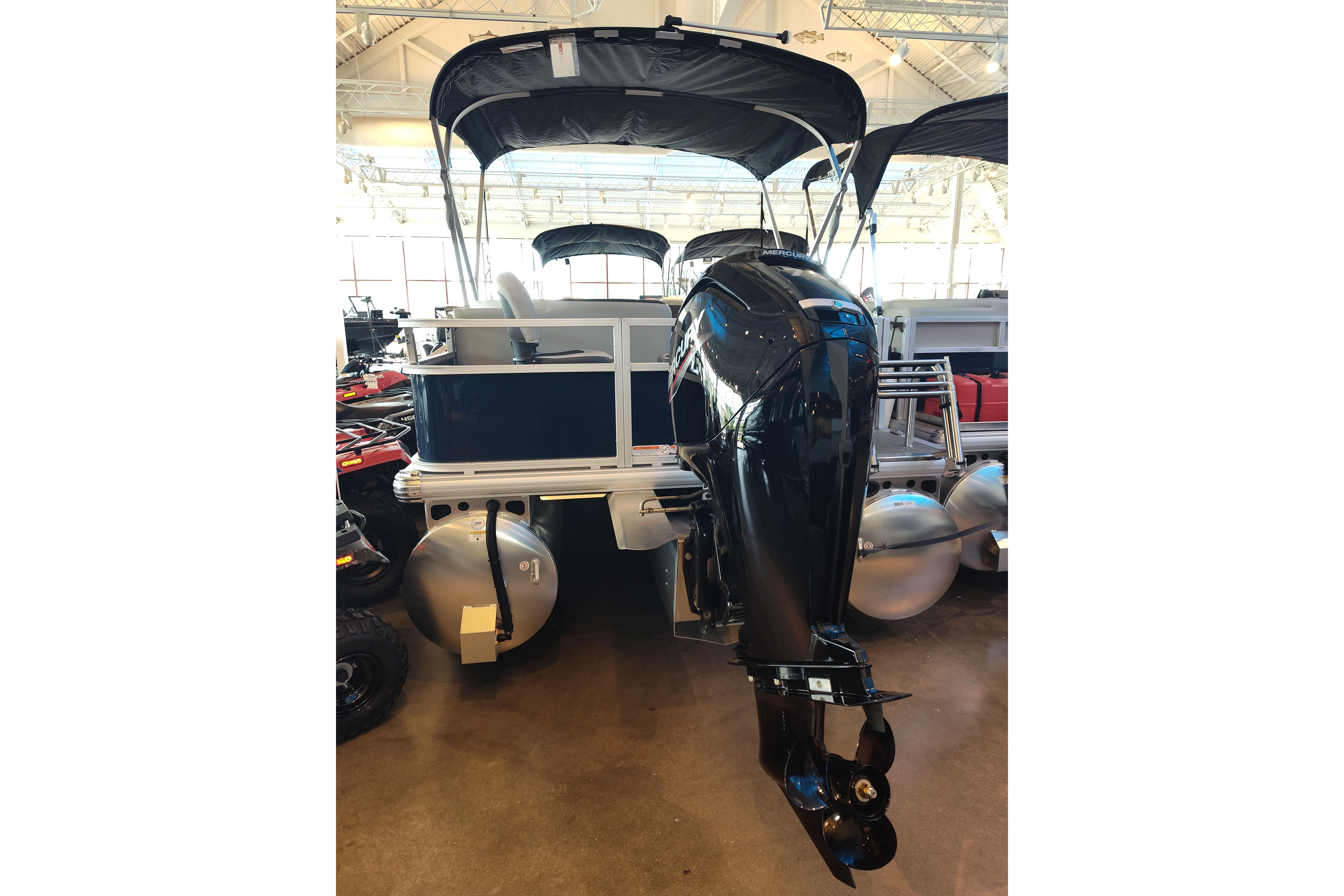 2026 Sun Tracker Bass Buggy 18 DLX pontoon boat with outboard motor in showroom.