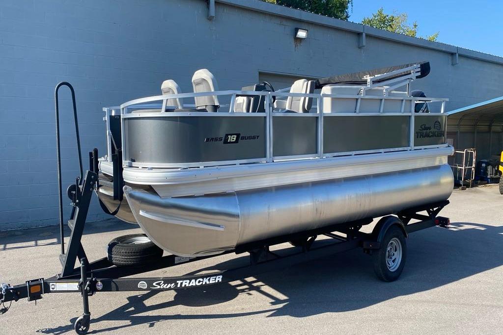 2026 Sun Tracker Bass Buggy 18 DLX pontoon boat on trailer, parked outdoors.