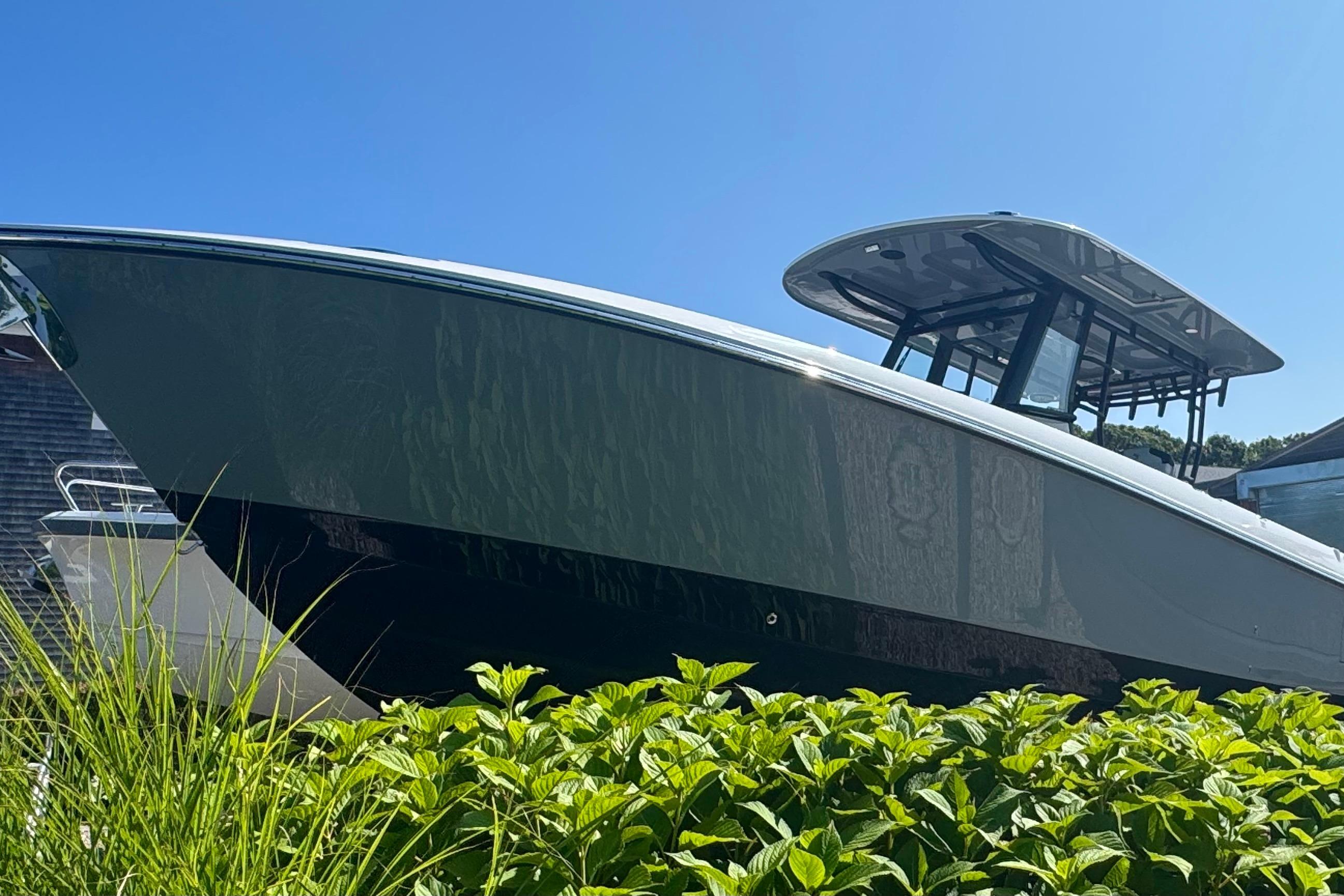 2025 Edgewater 340CC boat with sleek design, docked near lush greenery under clear blue sky.