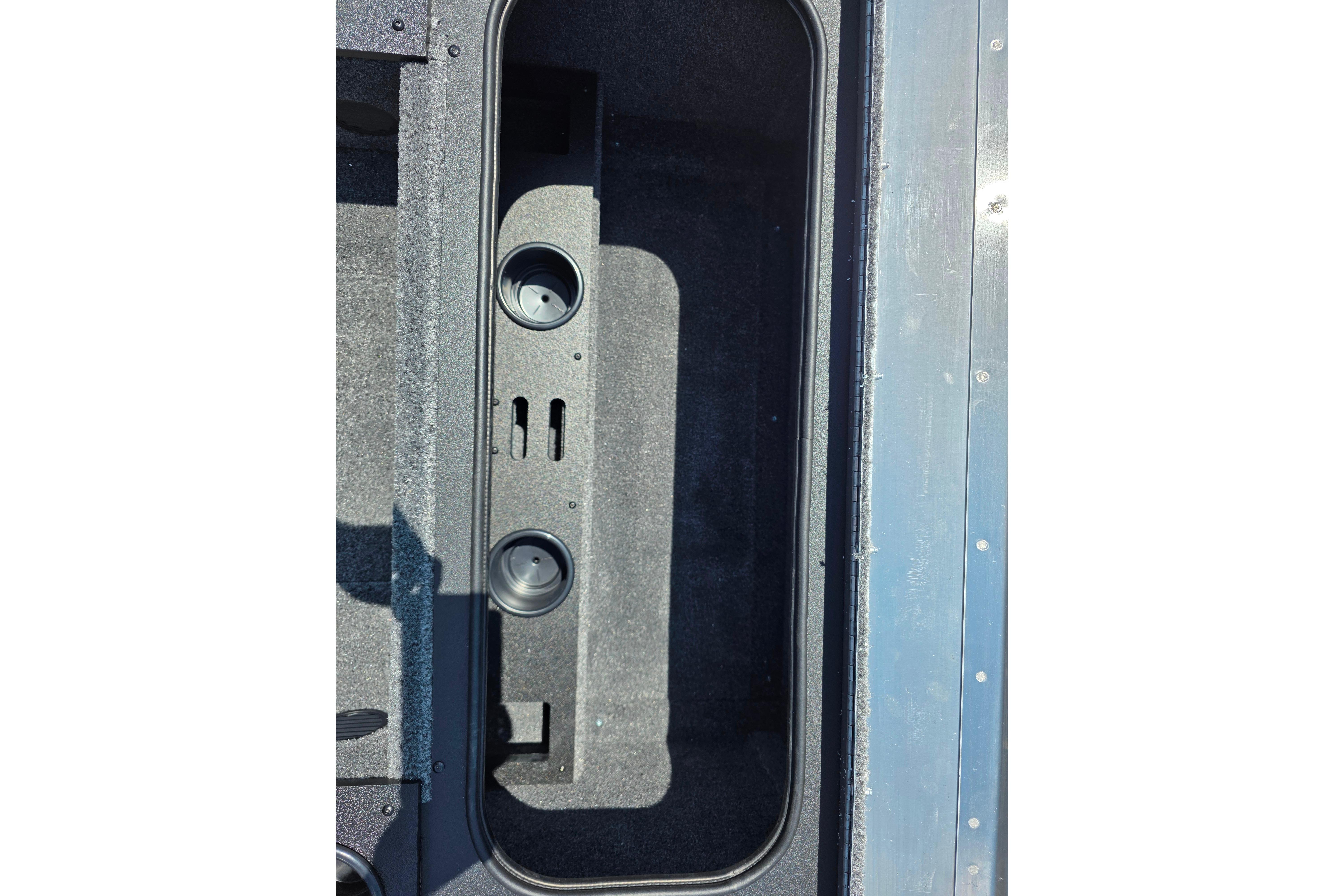 Storage compartment of 2026 Tracker Pro Team 195 boat, featuring cup holders and carpeted interior.