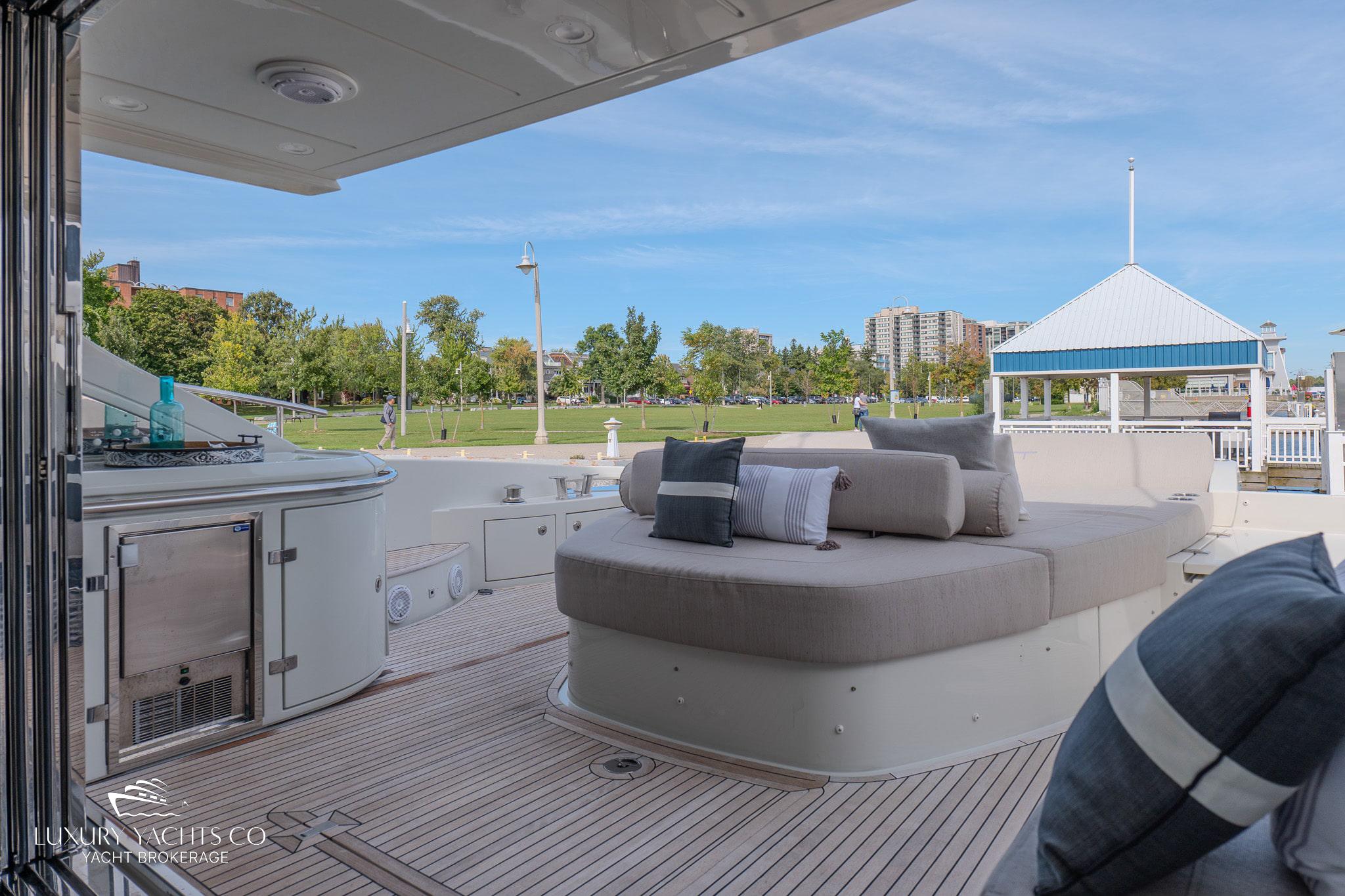 Luxurious 2010 Azimut 62S yacht deck with plush seating and scenic marina view.
