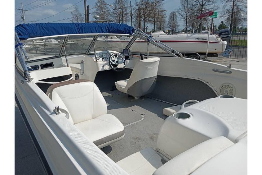 2008 Bayliner 175 boat interior with white seating and blue canopy, parked outdoors.