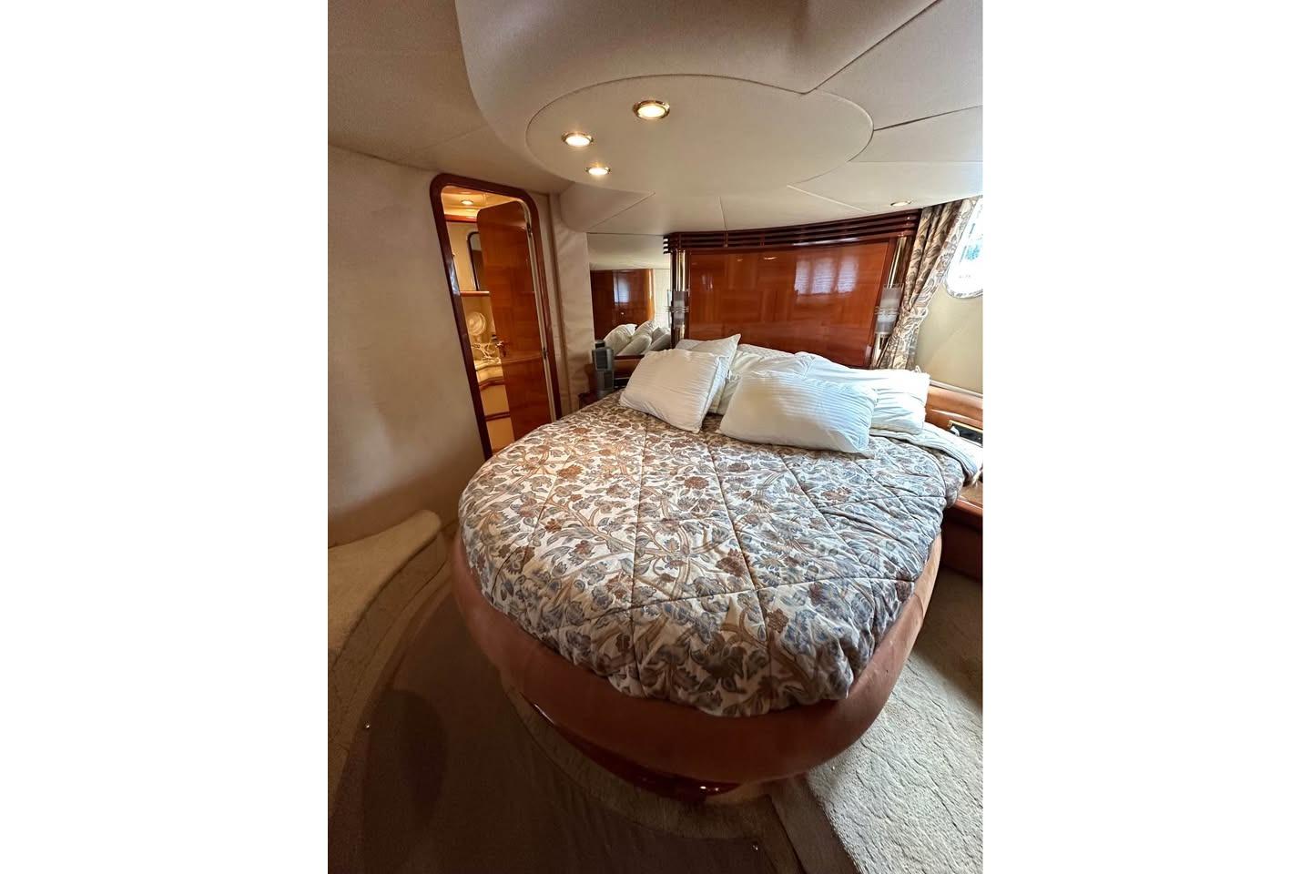Luxurious bedroom interior of 2004 Azimut 55E yacht with elegant bedding and wood accents.