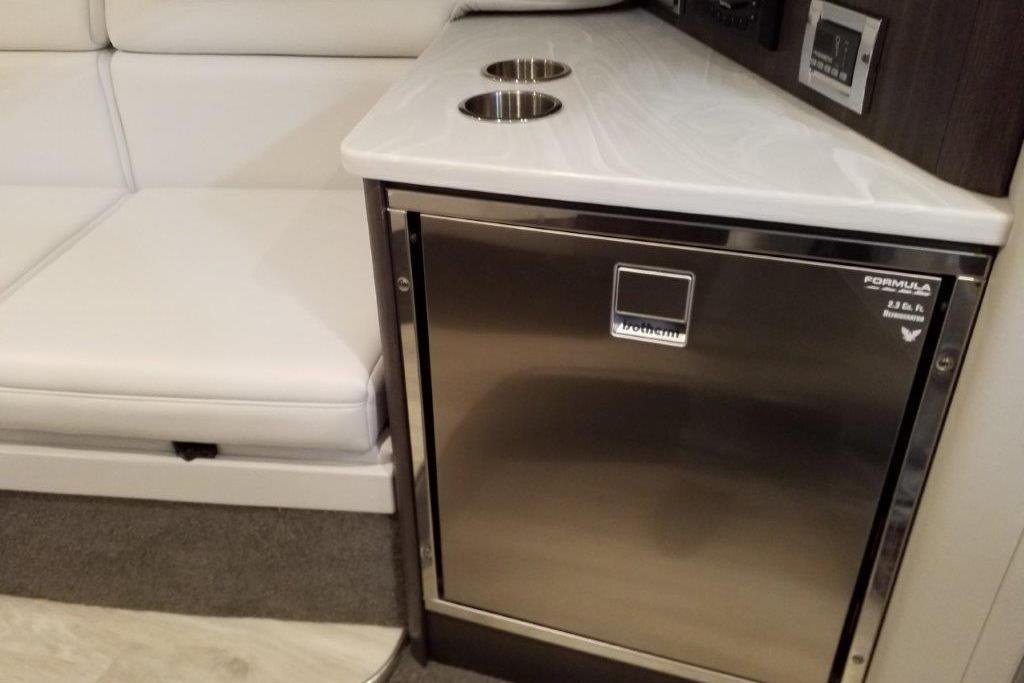 Interior of 2021 Formula 350 Sun Sport with stainless steel fridge and white seating.