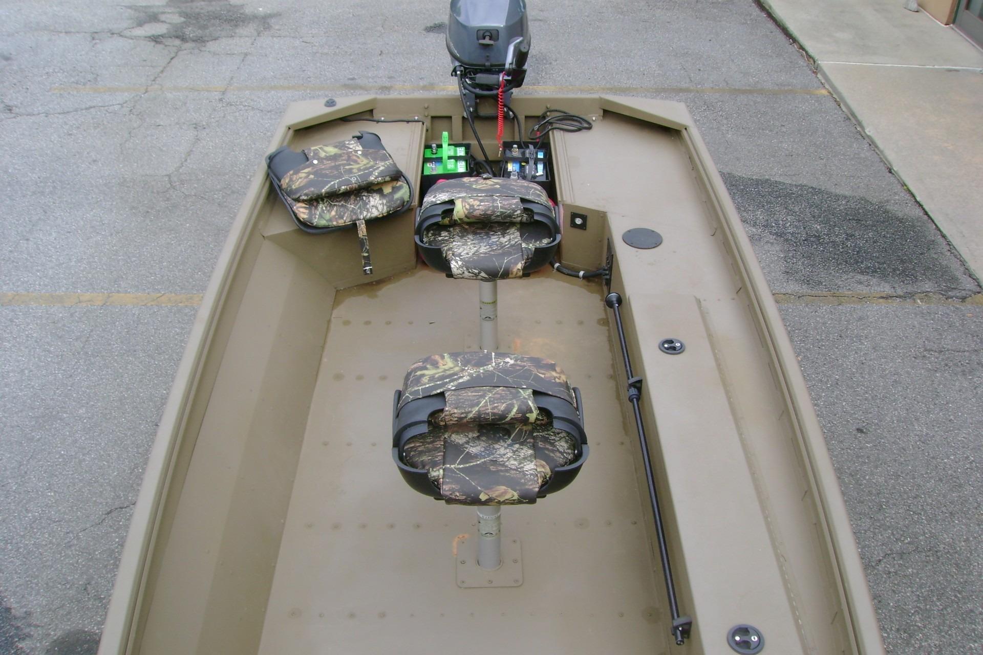 2023 G3 1652 DK boat interior with camouflage seats and motor, parked on pavement.