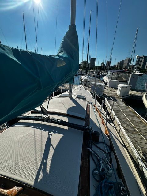 A 1985 Catalina 27 sailboat docked in a marina, surrounded by other boats.