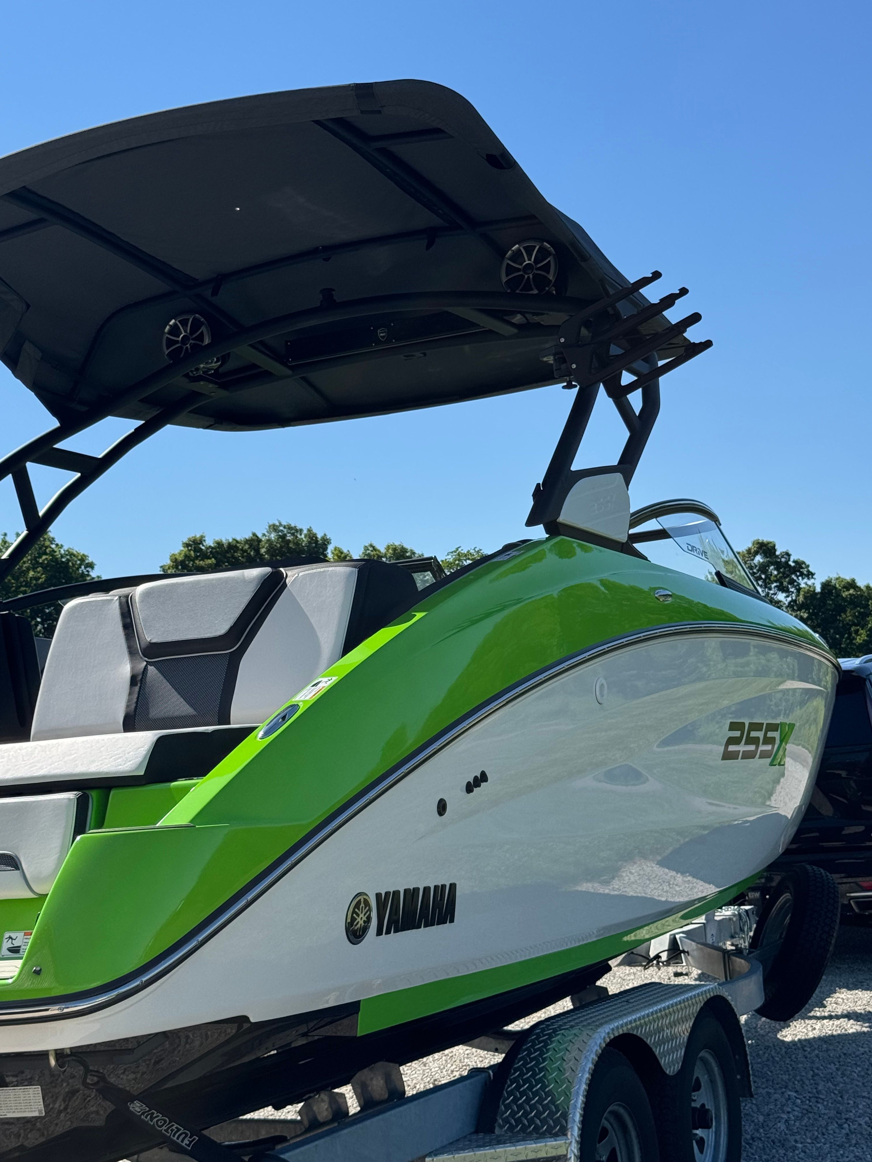 Yamaha 255XD boat from 2022 on a trailer, green and white with a black canopy.