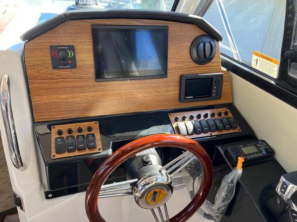 2025 Cutwater C-248 C Coupe helm with wood paneling, steering wheel, and electronic controls.