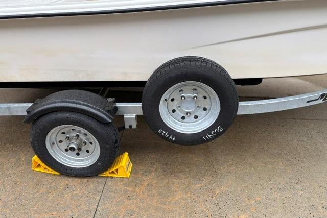 Trailer wheels of a 2025 Mako Pro Skiff 13 CC, secured with yellow chocks.