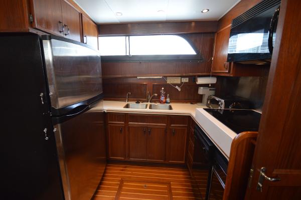 The 1980 Hatteras 53 Yacht Fisherman kitchen features wooden cabinets, a sink, and modern appliances.