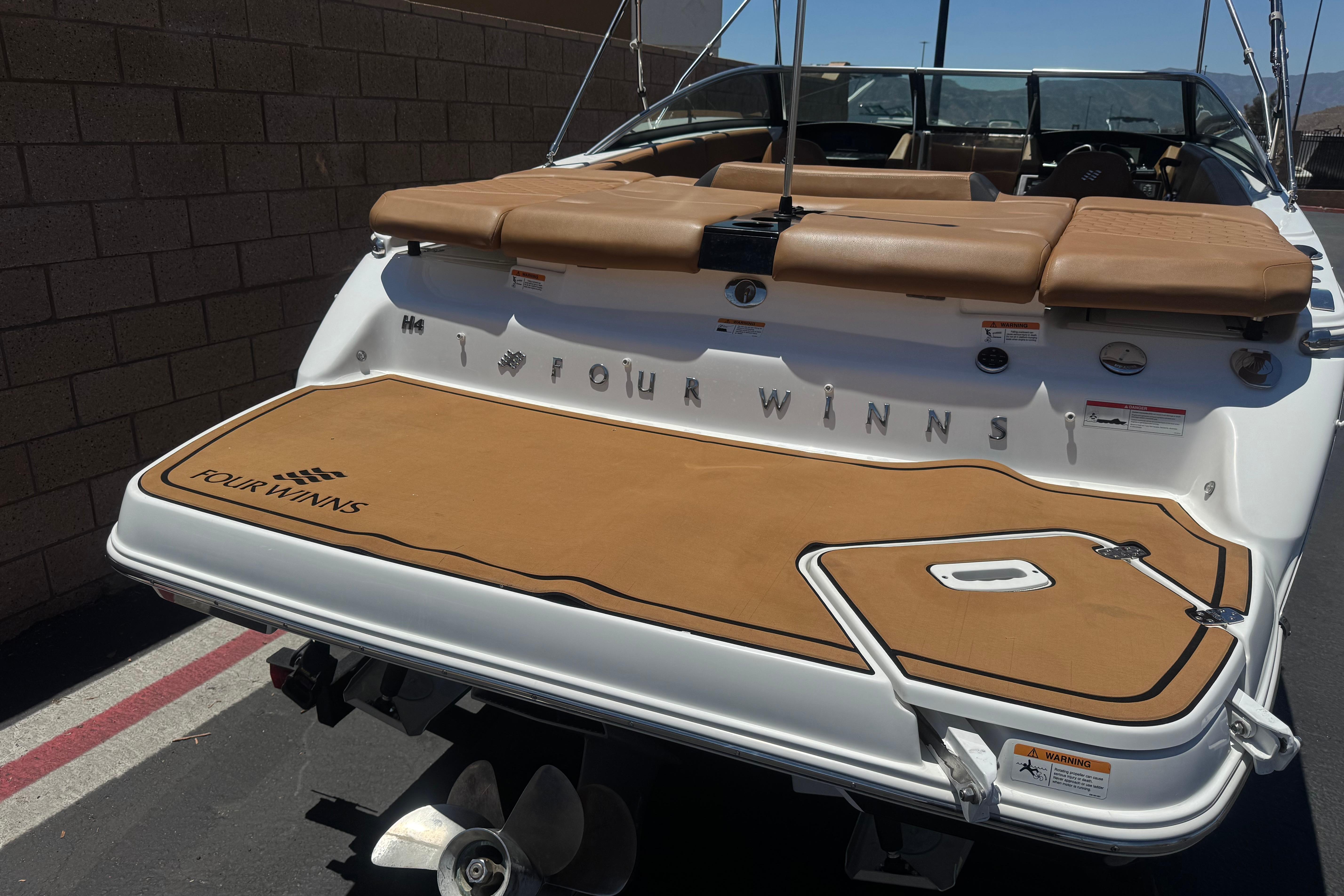 2022 Four Winns H4 boat with tan deck and seating, docked near a brick wall.